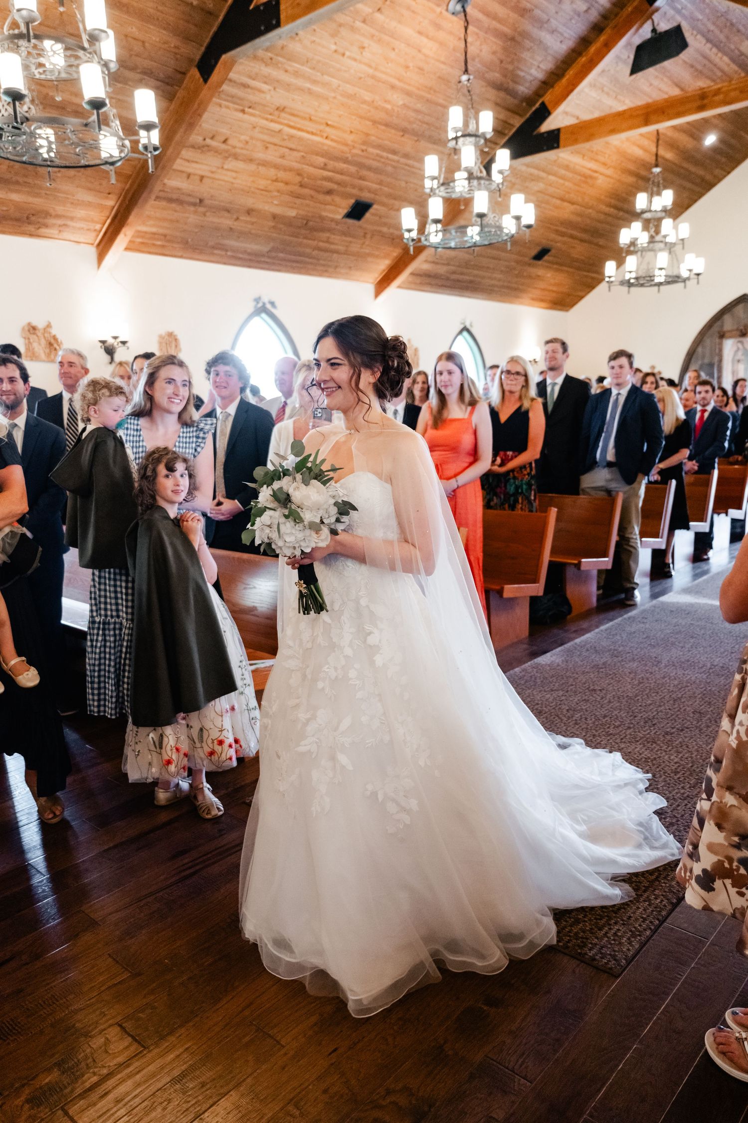 A beautiful wedding celebration with guests watching a couple dance in a rustic wooden-beamed venue.