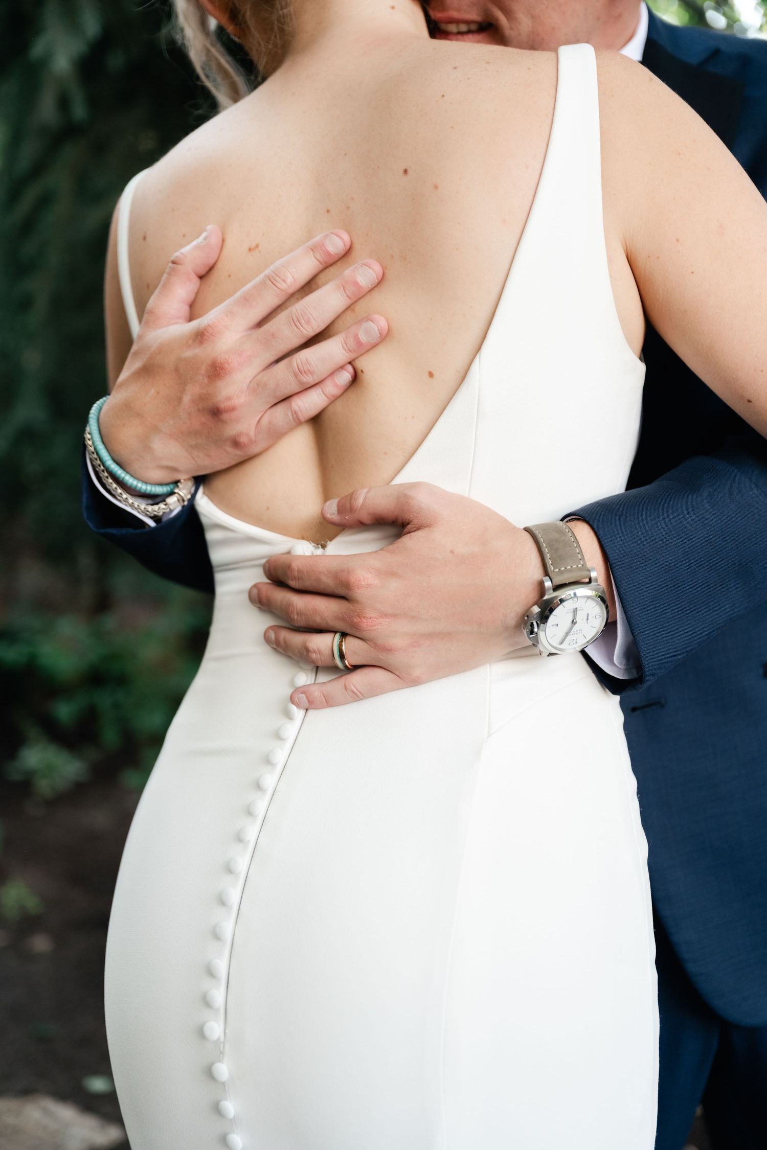 Close-up details of a white wedding dress with delicate button closures and elegant back design.