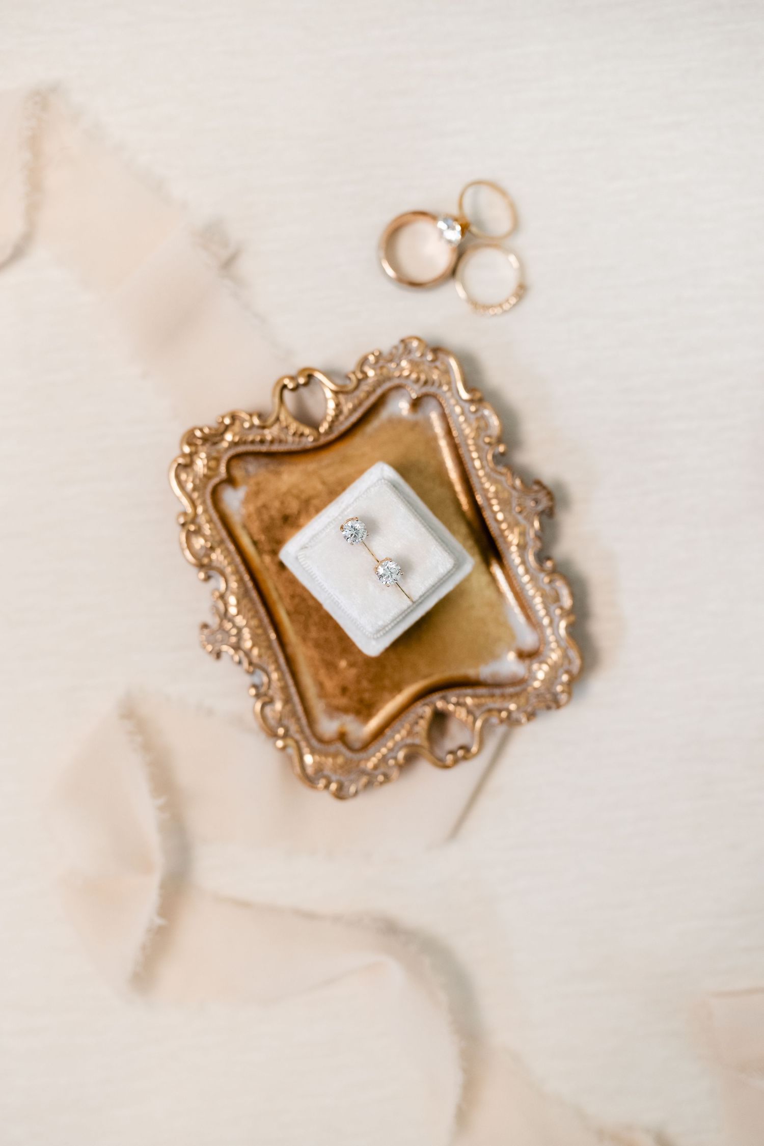 Ornate gold vintage frames displayed on white marble surface for wedding detail photography.