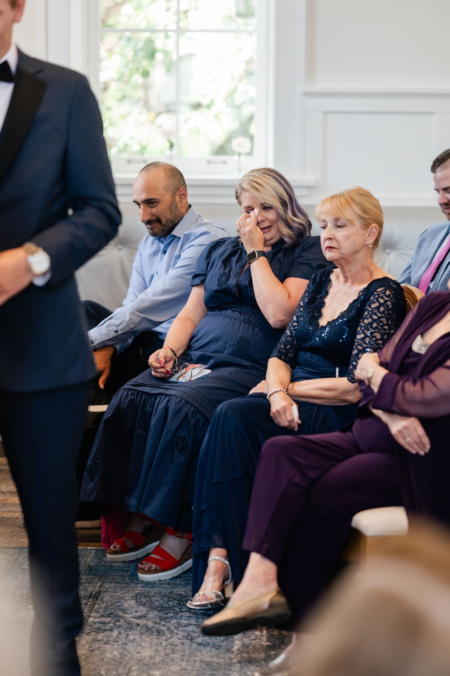 Attendees in formal attire sit on couches during what appears to be a business meeting or conference.