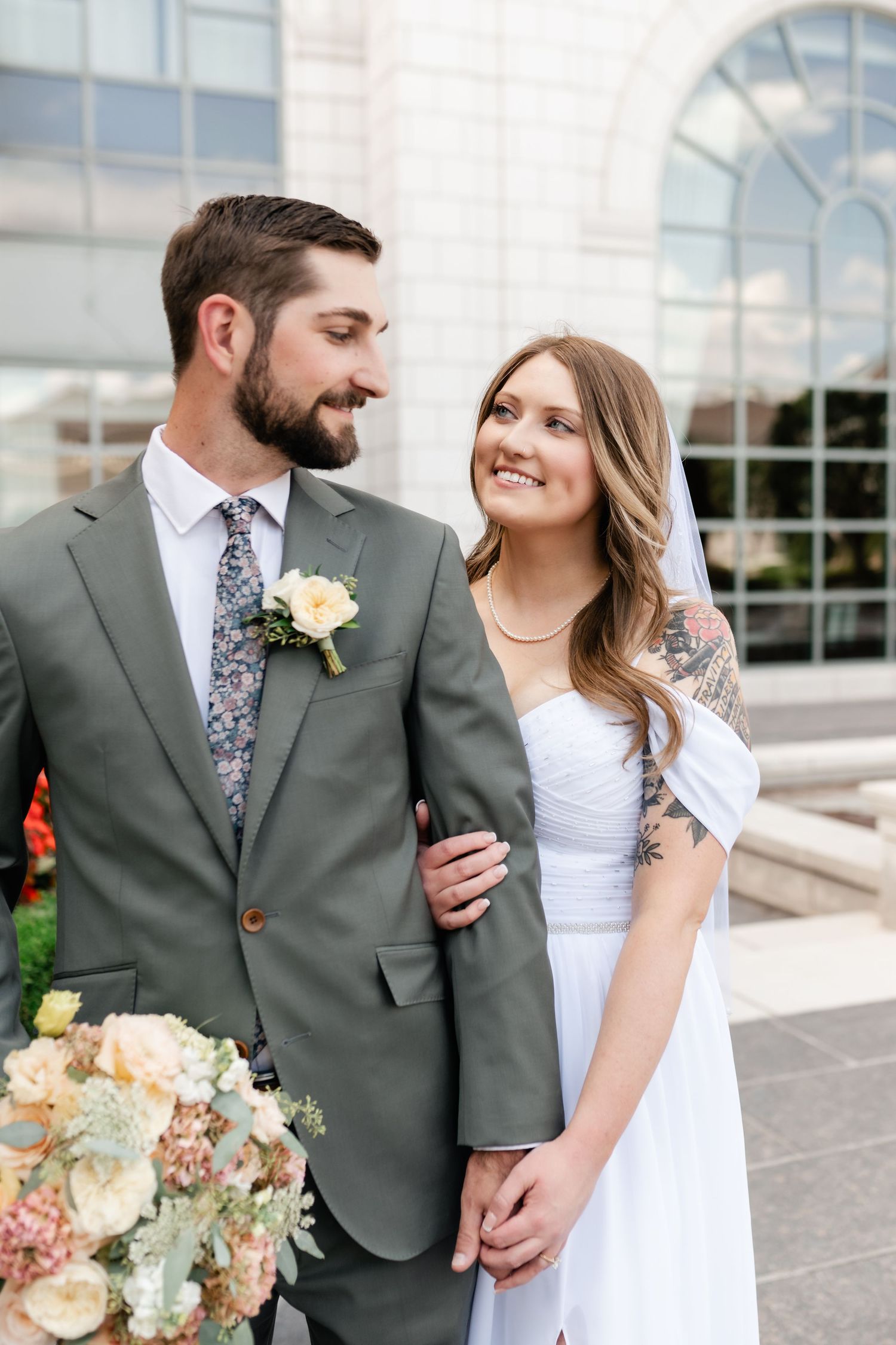 A wedding couple shares intimate moments in a series of romantic outdoor portraits with peach and white floral bouquet.