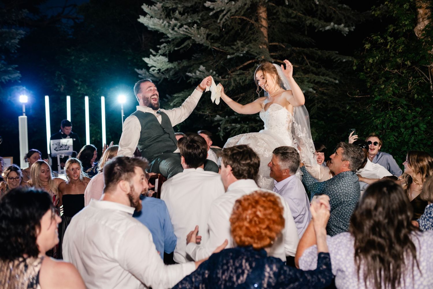 Wedding guests dance together on an outdoor dance floor during an evening reception celebration. Millcreek Inn Wedding Photographer.