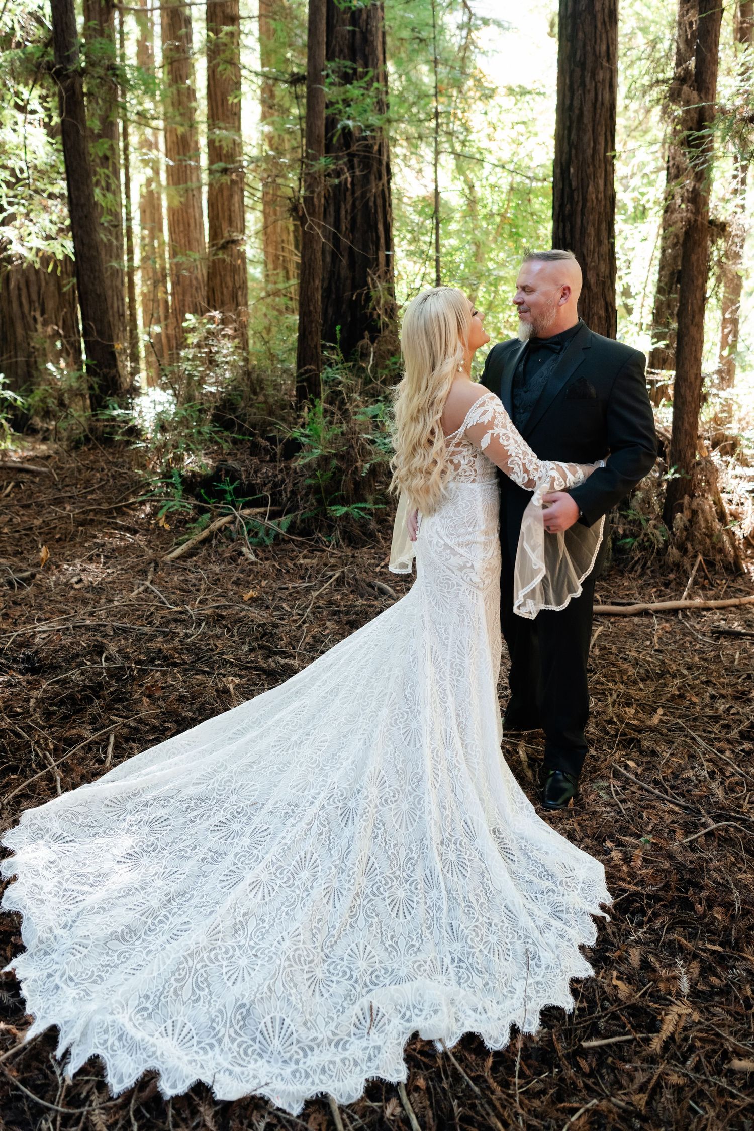 Stunning lace wedding dress with long train photographed in a serene redwood forest setting.