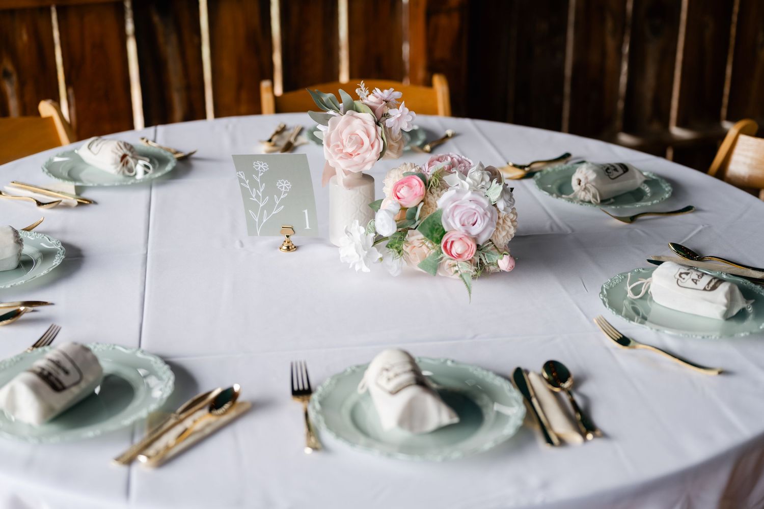 Elegant table setting with pale blue plates, delicate floral arrangements, and silver cutlery on white tablecloth.