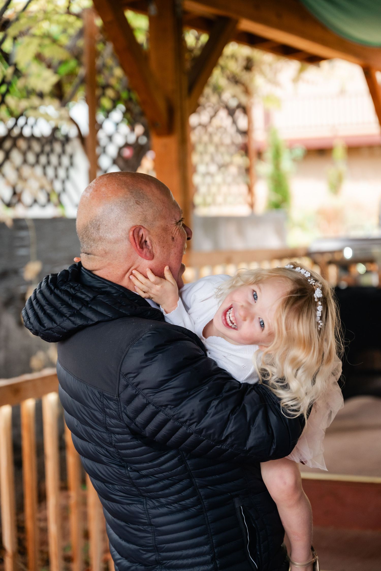 A joyful couple shares an intimate dance moment under a covered wooden pavilion.