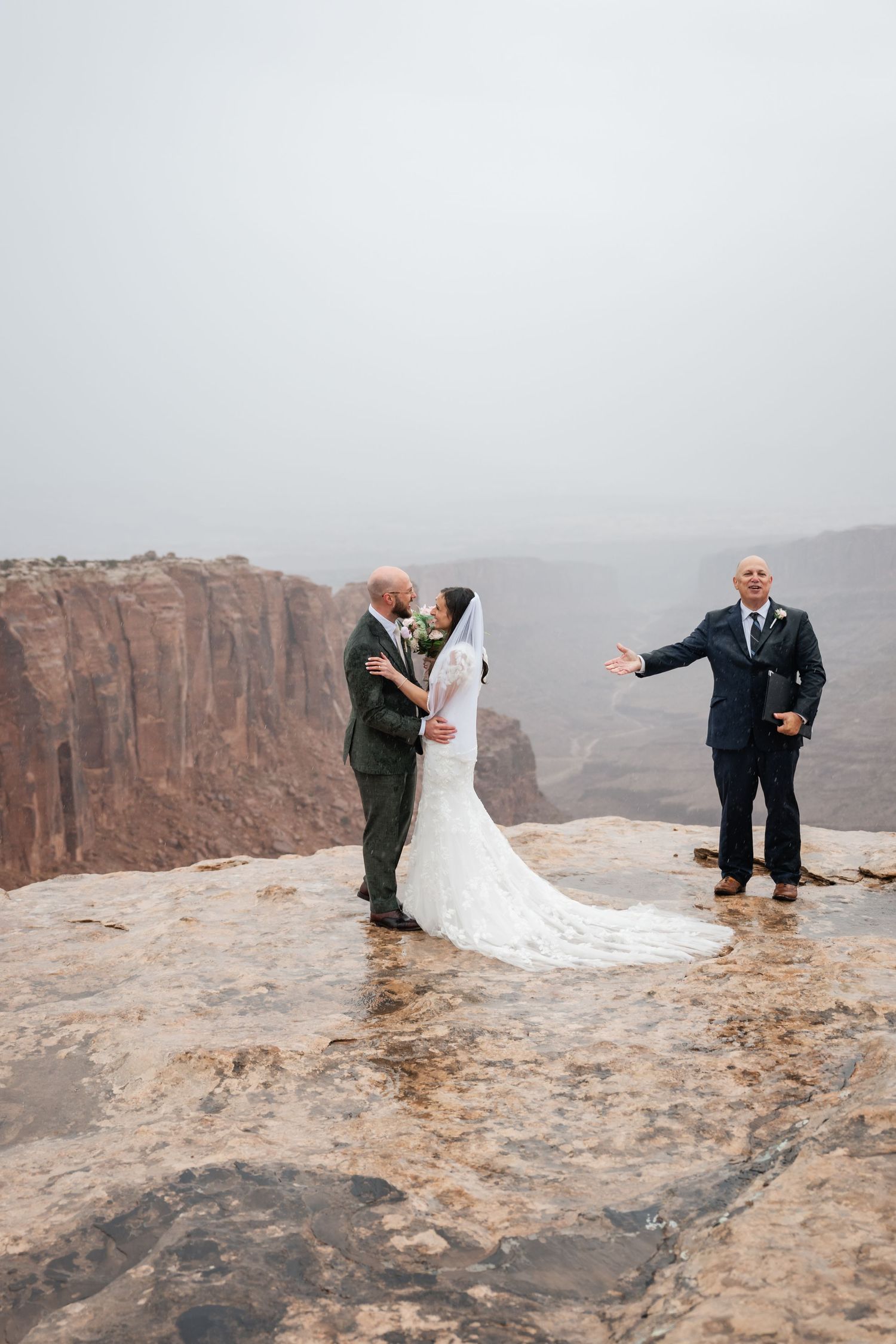 Newlyweds share intimate moments during their wedding photoshoot on a desert cliff overlook.