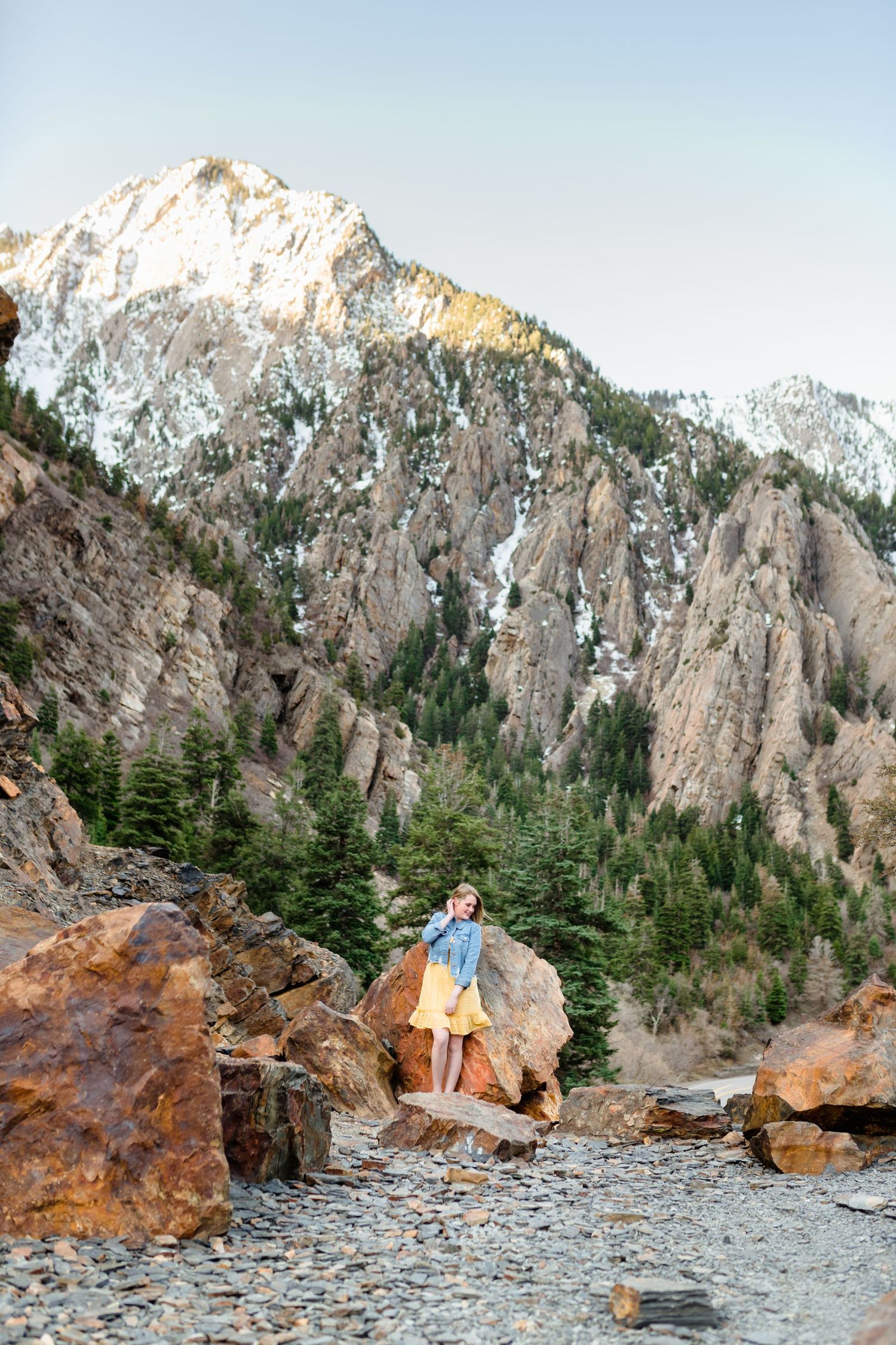 Scenic mountain landscape with rocky cliffs and evergreen trees in a rugged wilderness setting during golden hour.