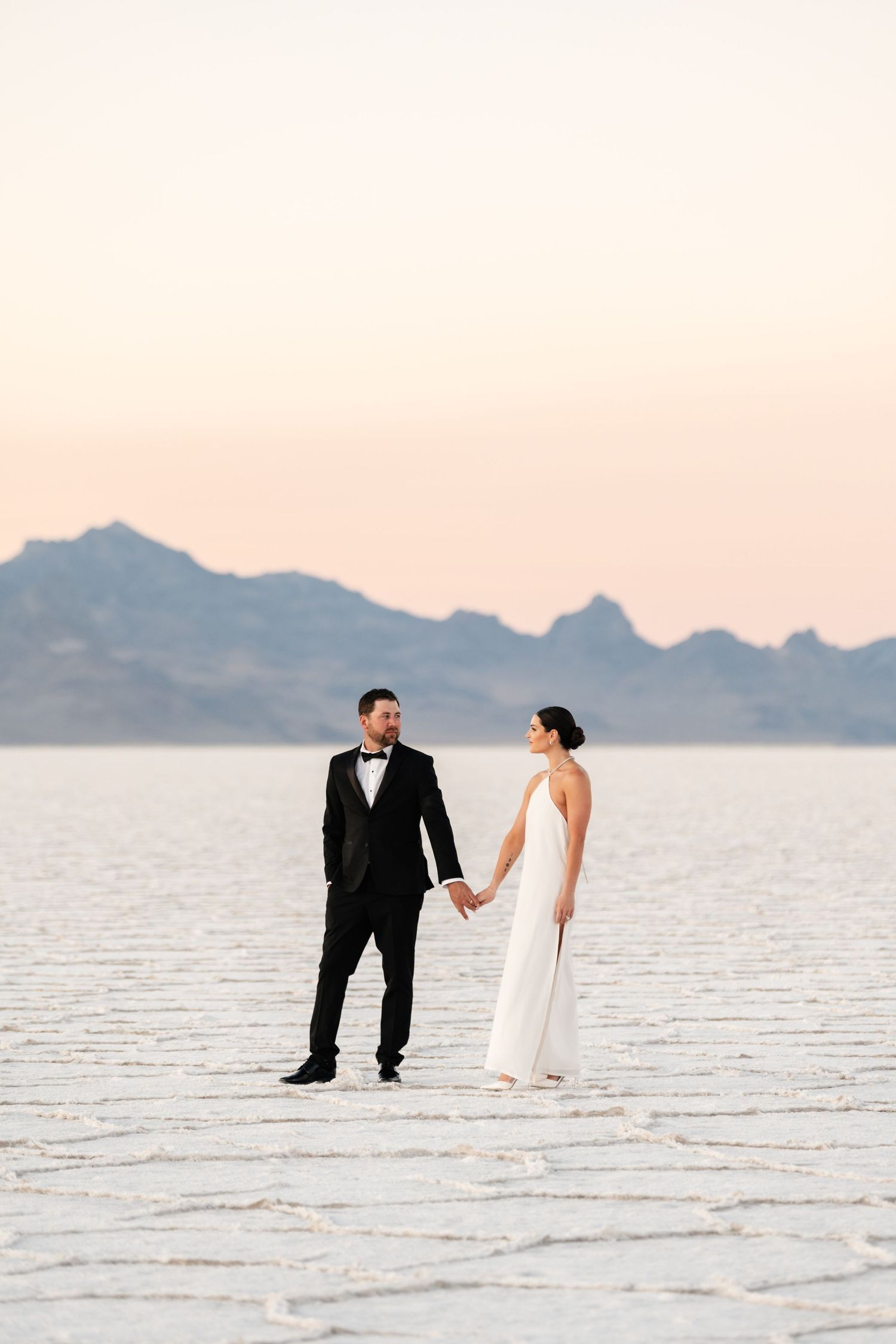Utah Salt Flats Photographer. A minimalist wedding photo on salt flats with mountains in the soft pink distance.