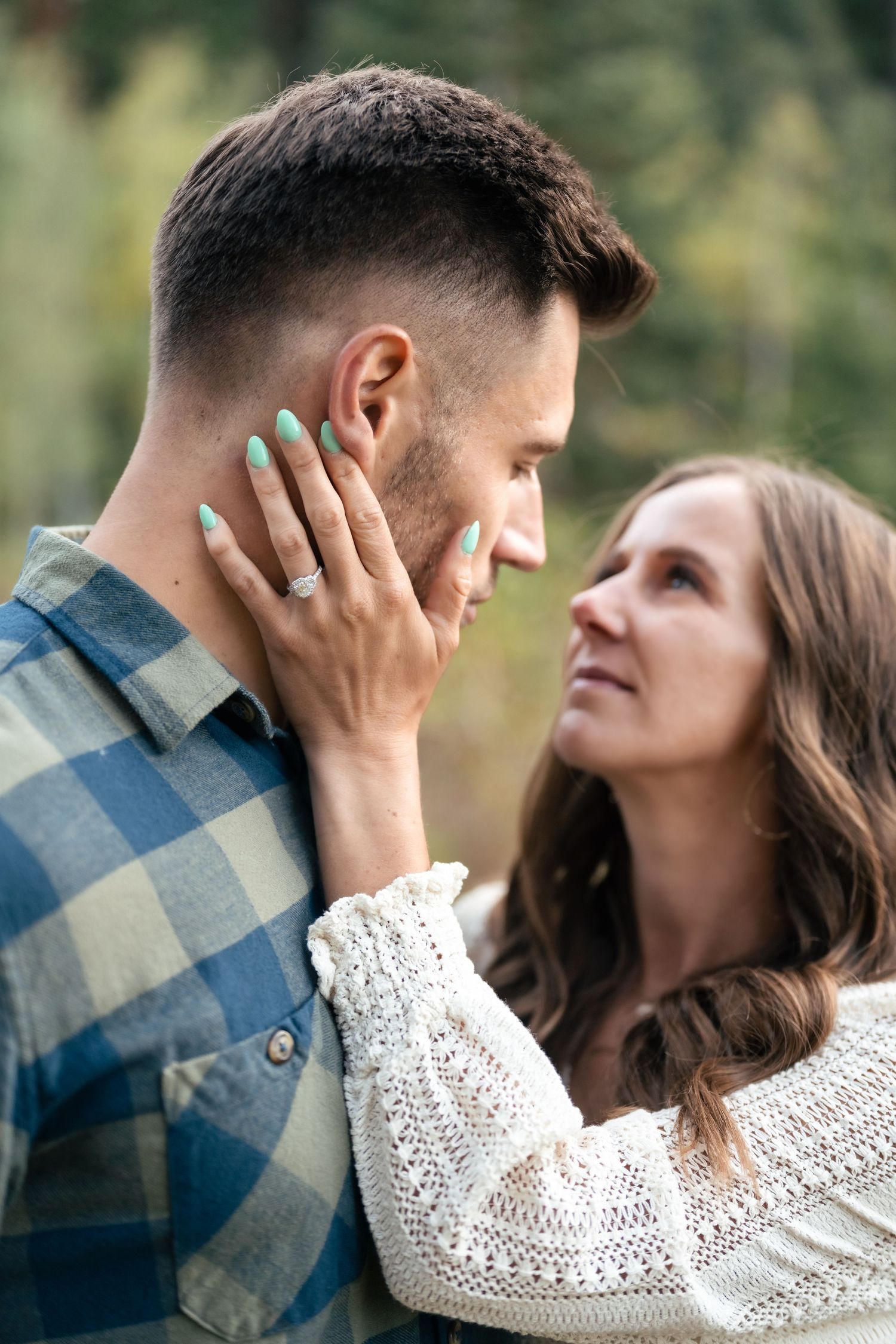 A tender moment between a couple in outdoor setting with woman in white sweater touching companion's face.