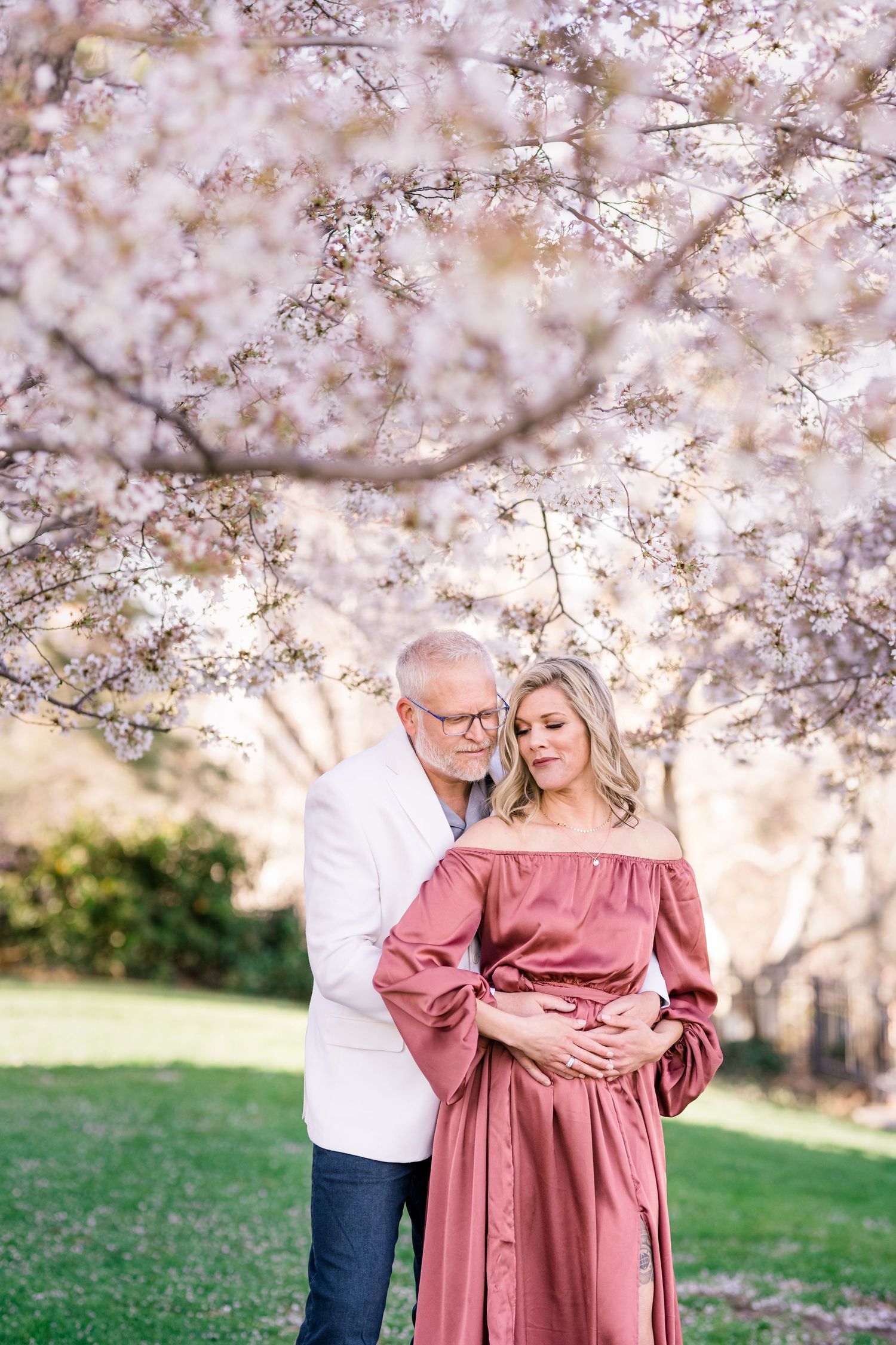 Engaged couple hug warmly at the Capitol cherry blossoms by Utah wedding photographer Coley Cook