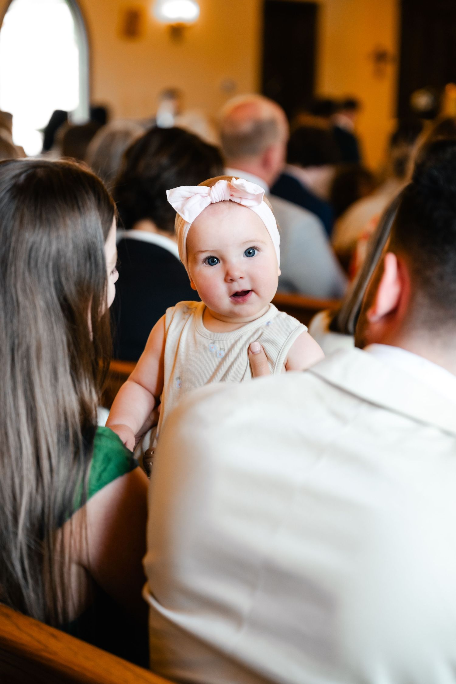 An adorable baby in white attire steals attention during a wedding ceremony.