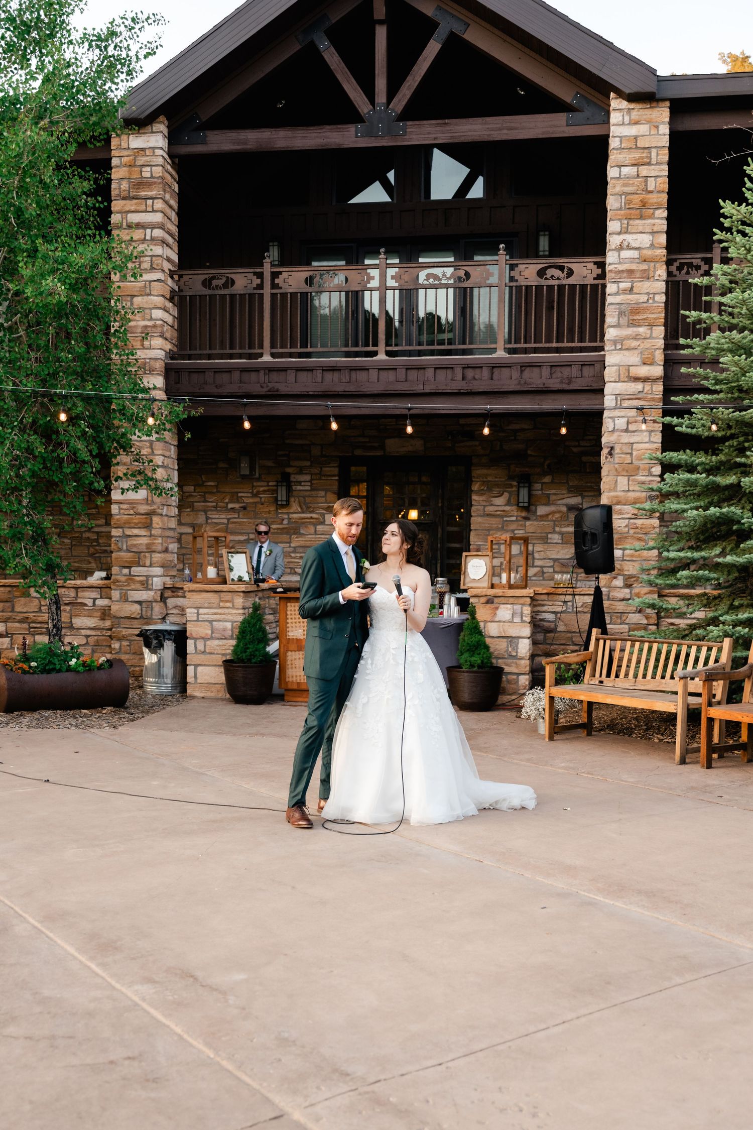 A romantic first dance moment captured under a rustic covered patio with brick pillars and wooden beams.
