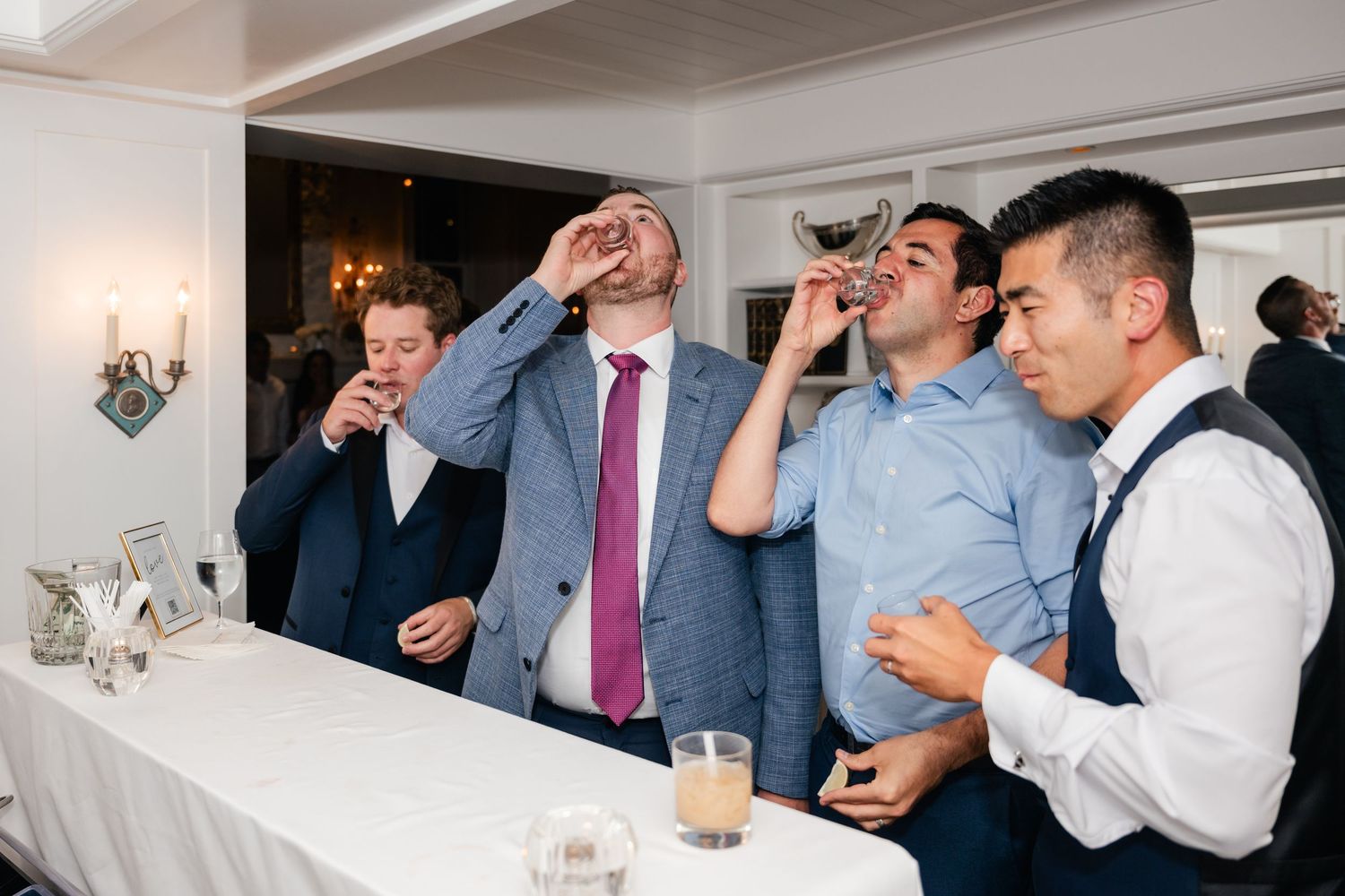 Wedding reception guests enjoying drinks and conversation in an indoor venue.