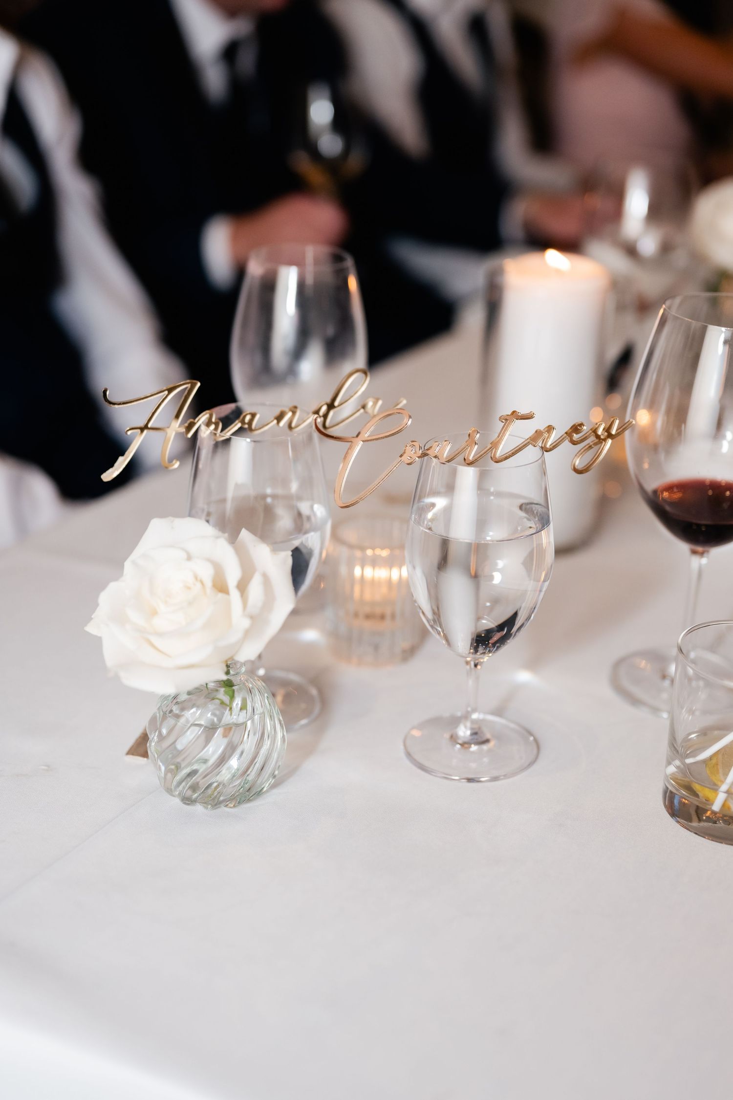 Elegant wine glasses and place settings arranged on a white tablecloth at a formal dining event.
