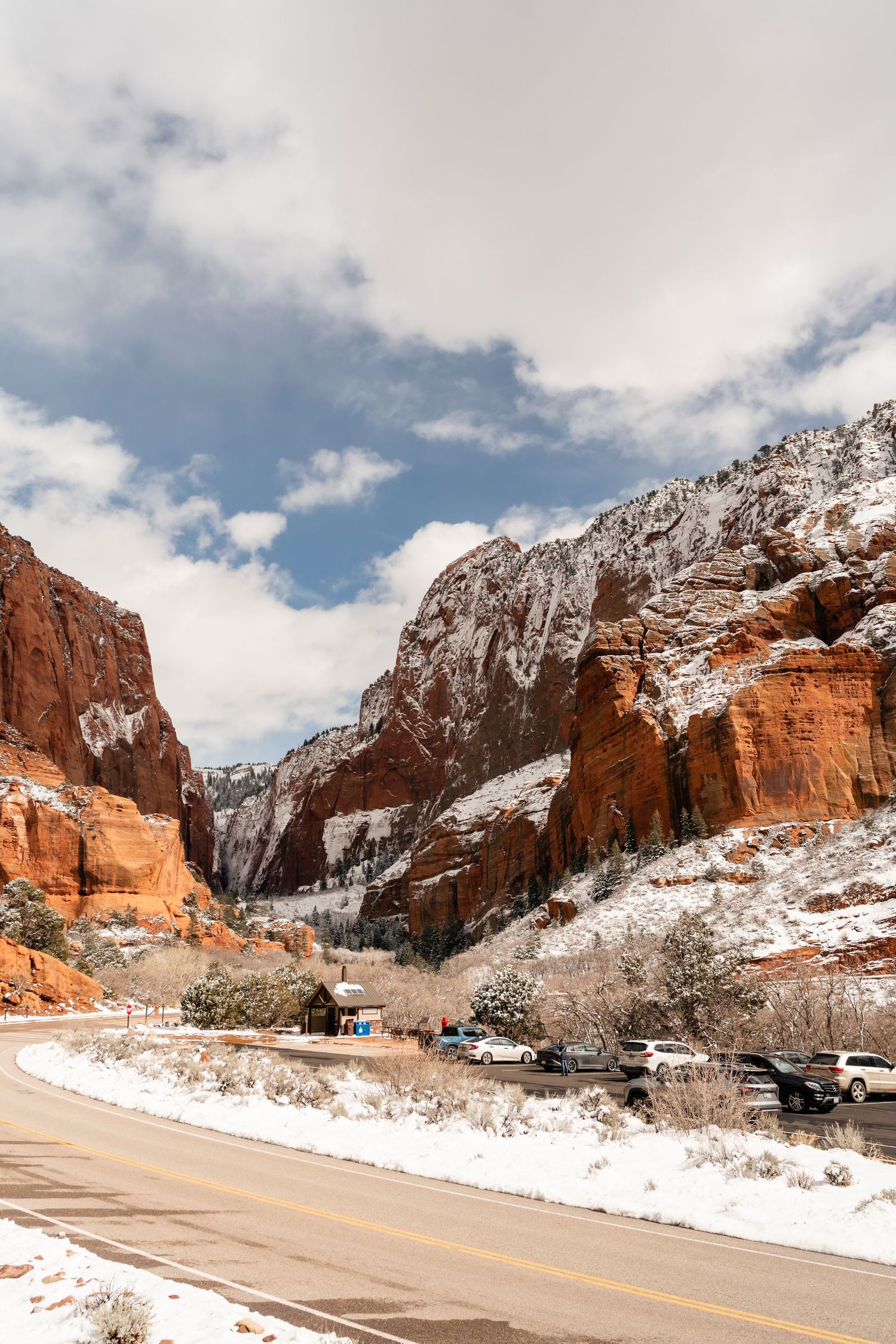 Snowy winter landscape of red rock cliffs and winding road through Zion National Park in Utah.