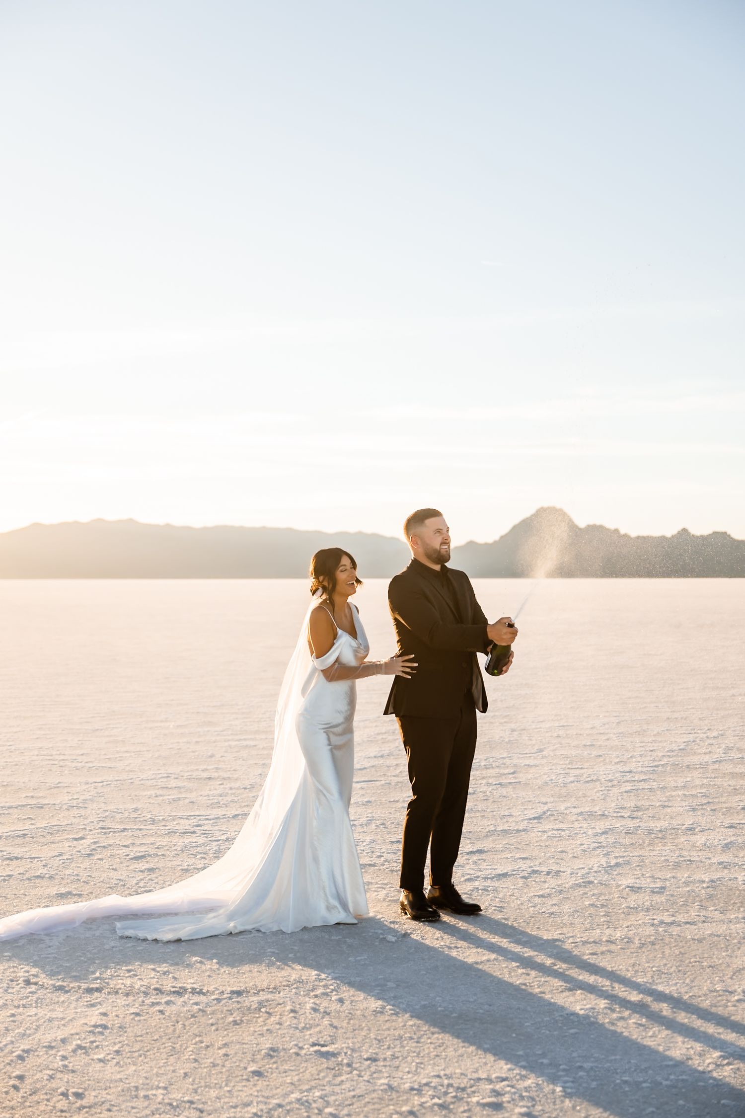A wedding couple shares a celebratory moment on the vast white salt flats.
