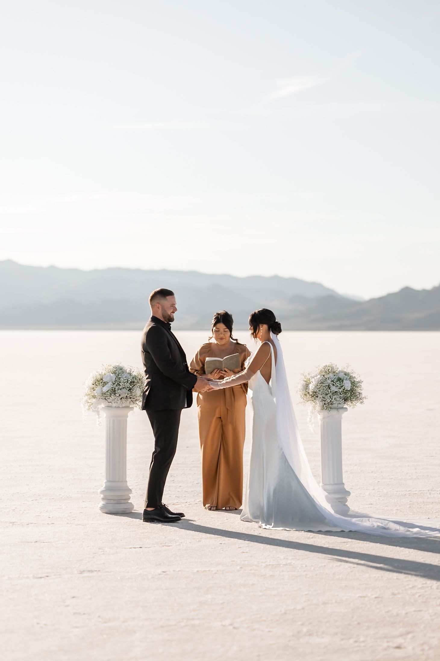 A wedding ceremony on a white salt flat with decorative pillars during their wedding ceremony. Utah Salt Flats Photographer.