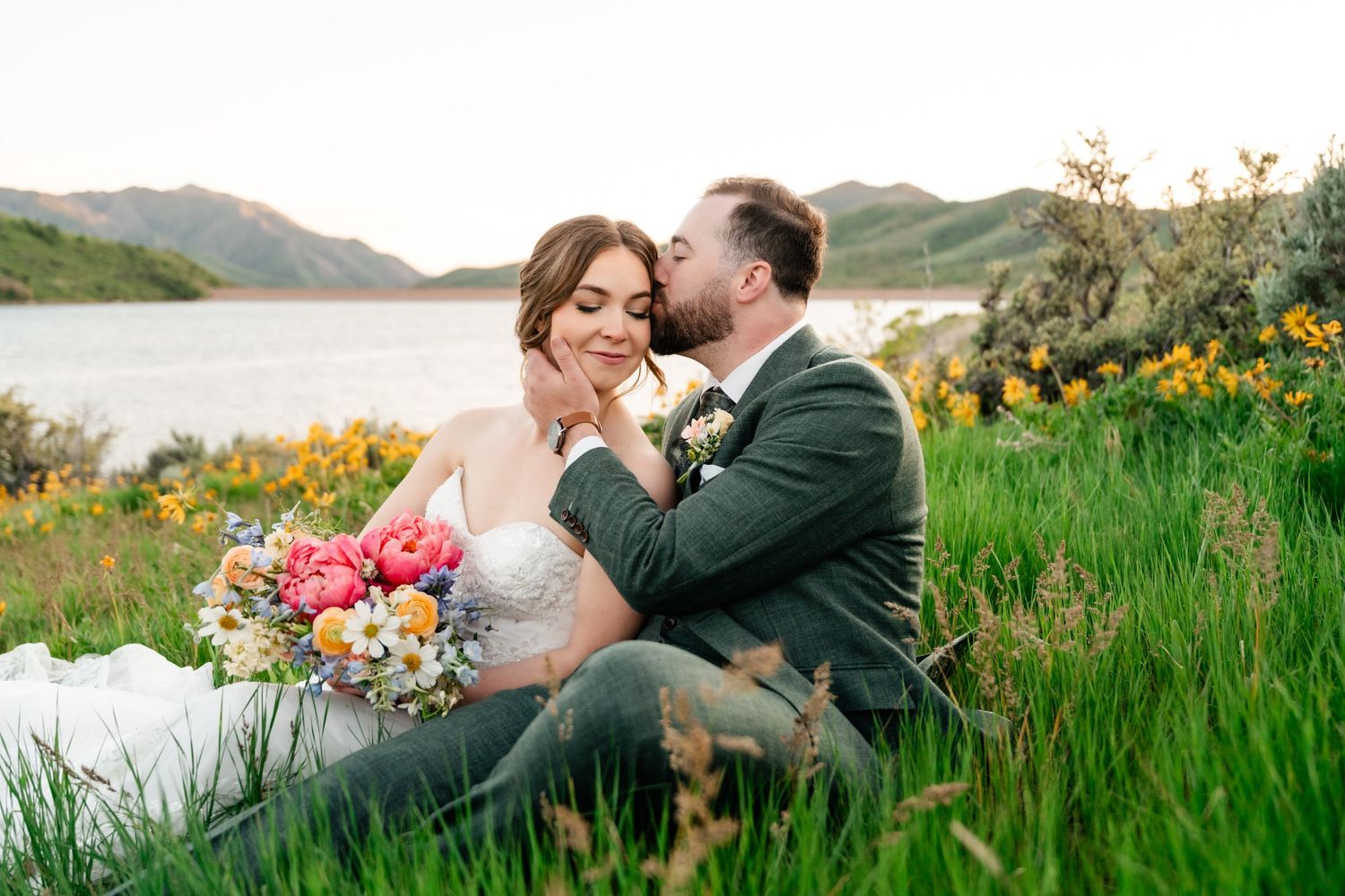 Romantic wedding portraits in mountain meadow with wildflowers at sunset.