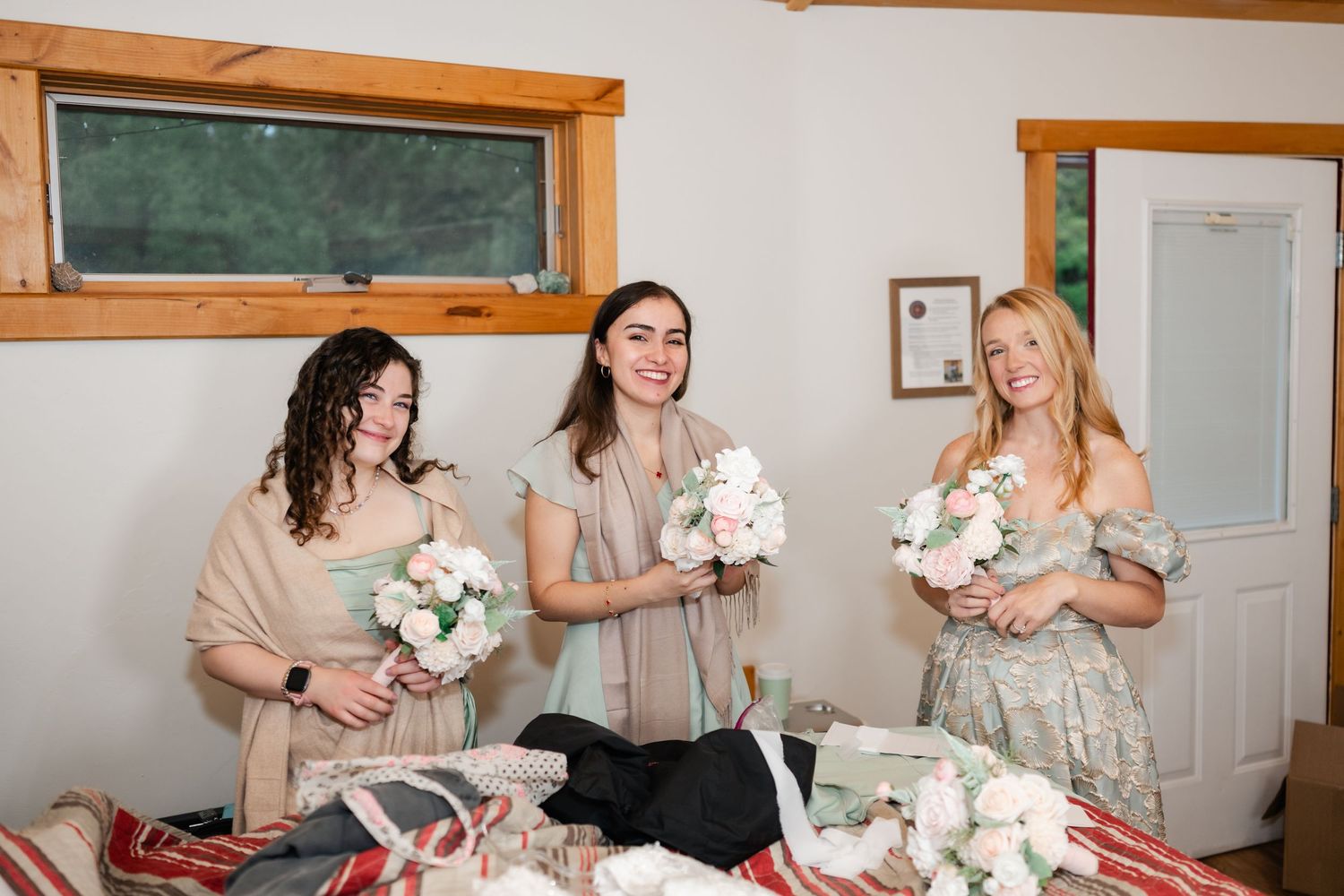 Wedding party members in pink bridesmaid dresses prepare for the ceremony in a room.