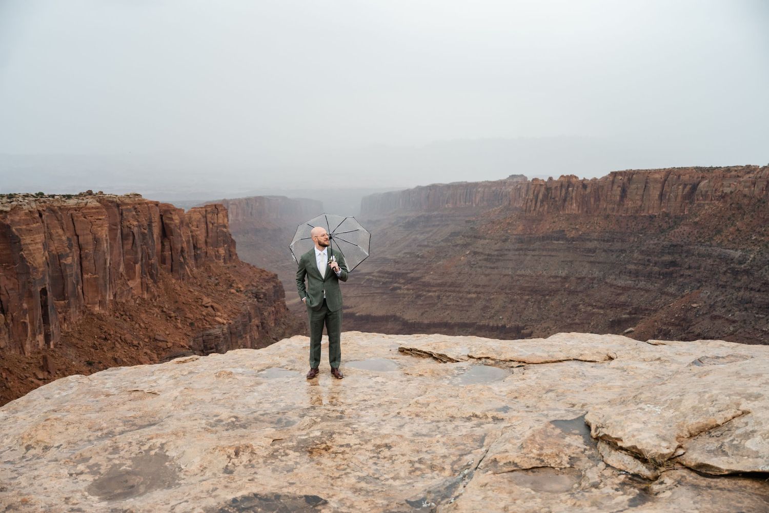 Panoramic view of multiple hikers exploring the vast red rock cliffs and canyons of Dead Horse Point State Park in Utah.