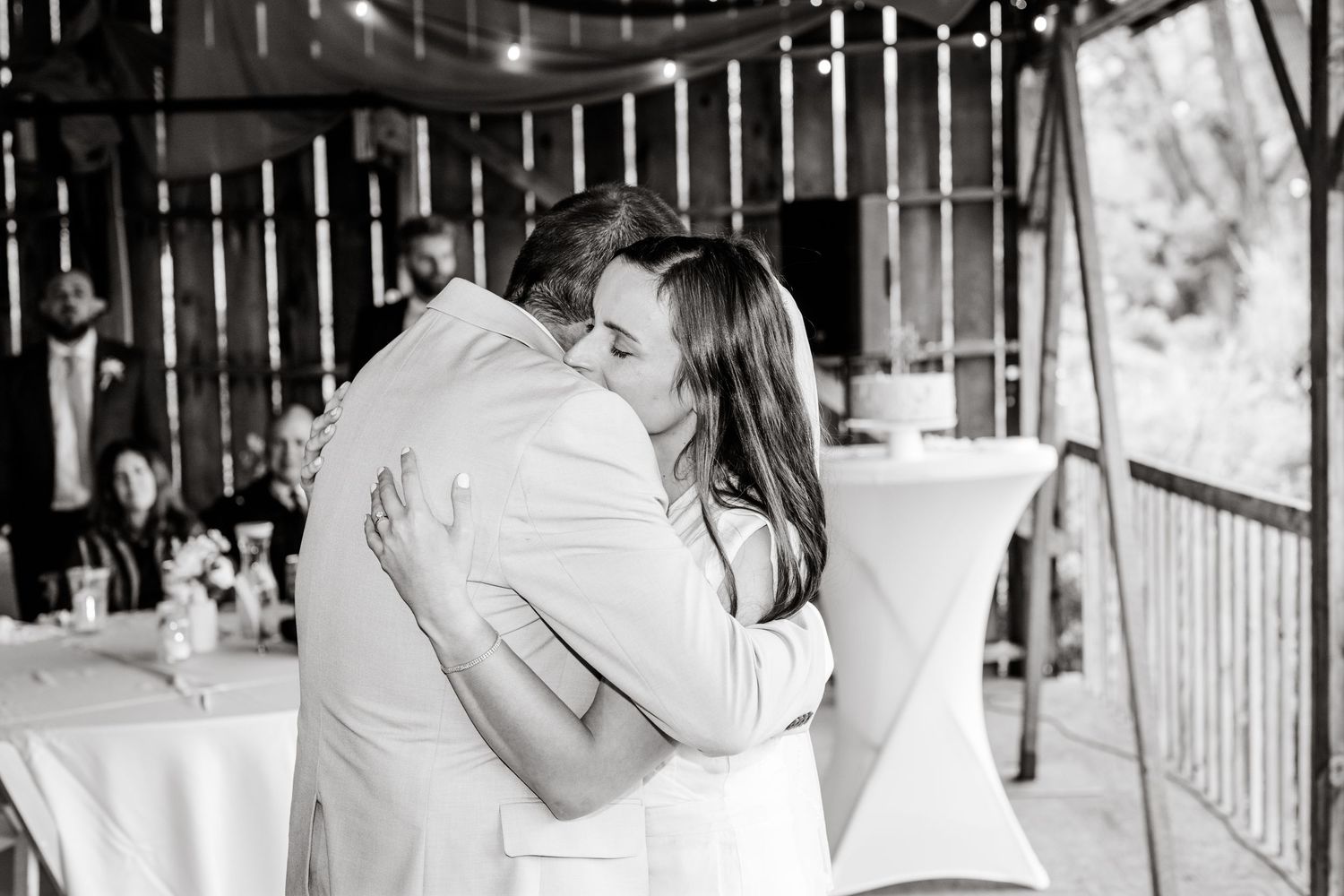 A black and white photograph of a couple embracing during their wedding celebration.