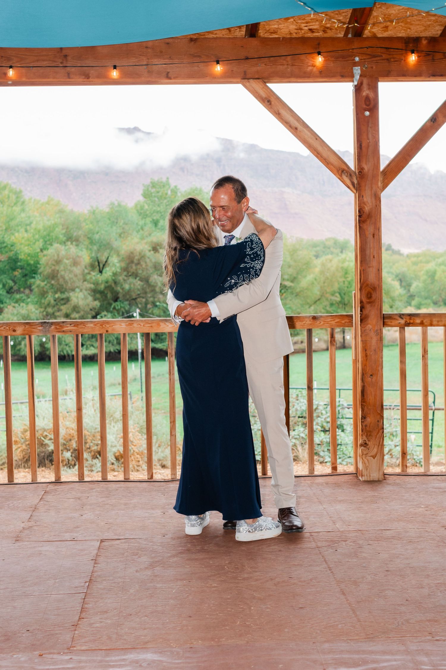 Couples dancing on a rustic wooden pavilion deck with scenic views.