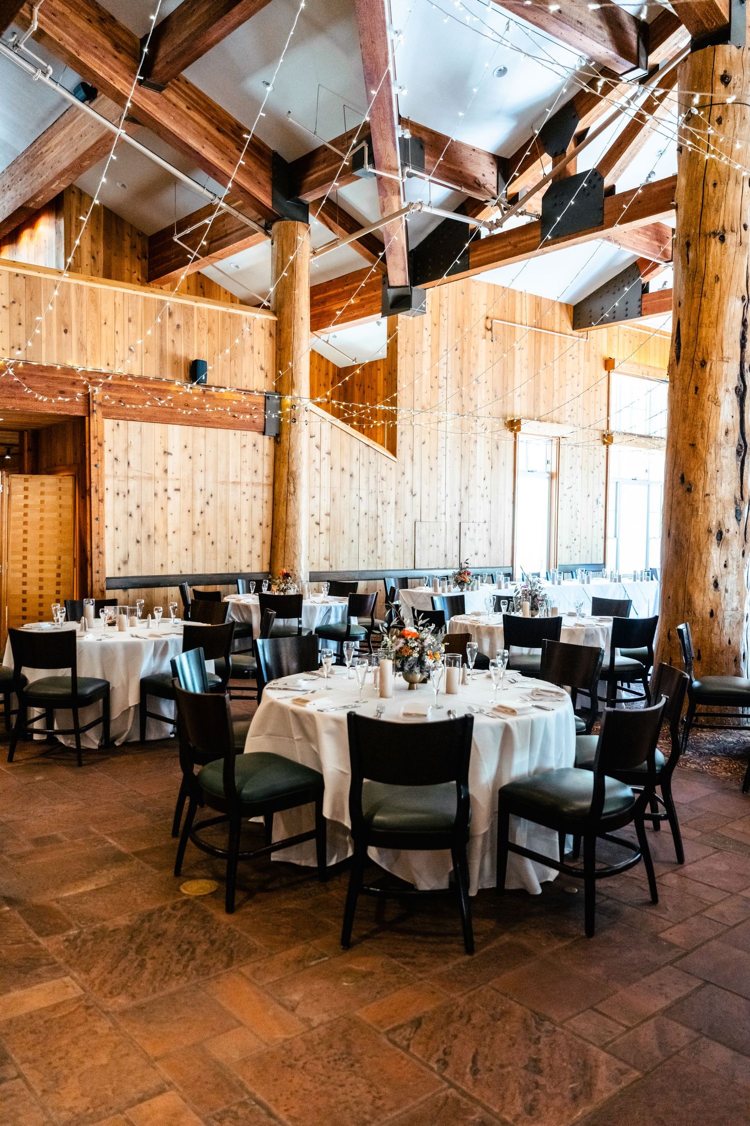 Rustic mountain lodge reception venue with wooden beams and round dining tables set for an elegant event.