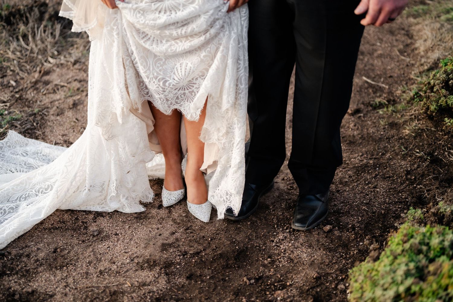 Detail shot of a white lace wedding dress against rocky coastal terrain.