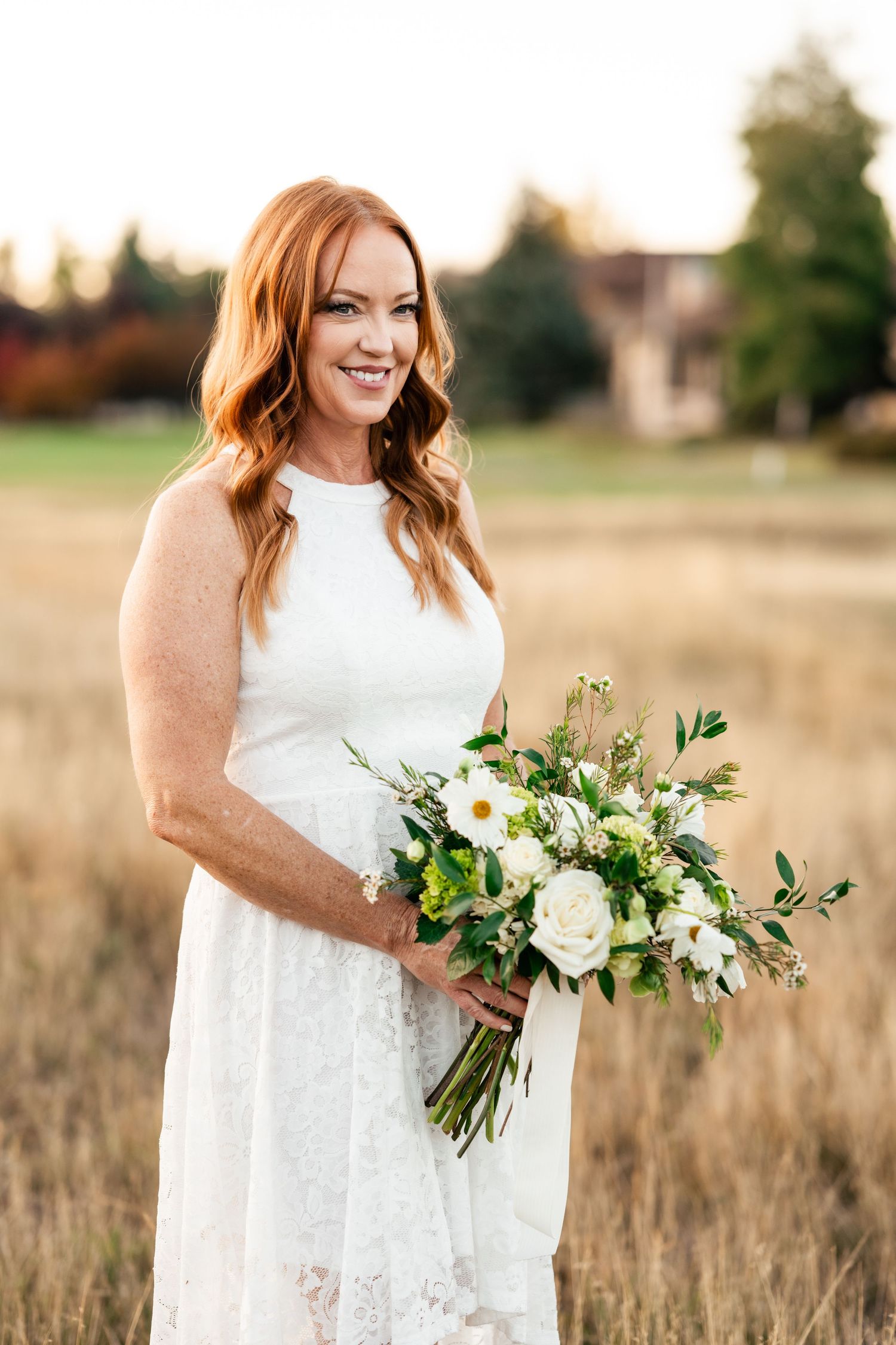 A white lace dress and beautiful bouquet of white flowers and greenery.