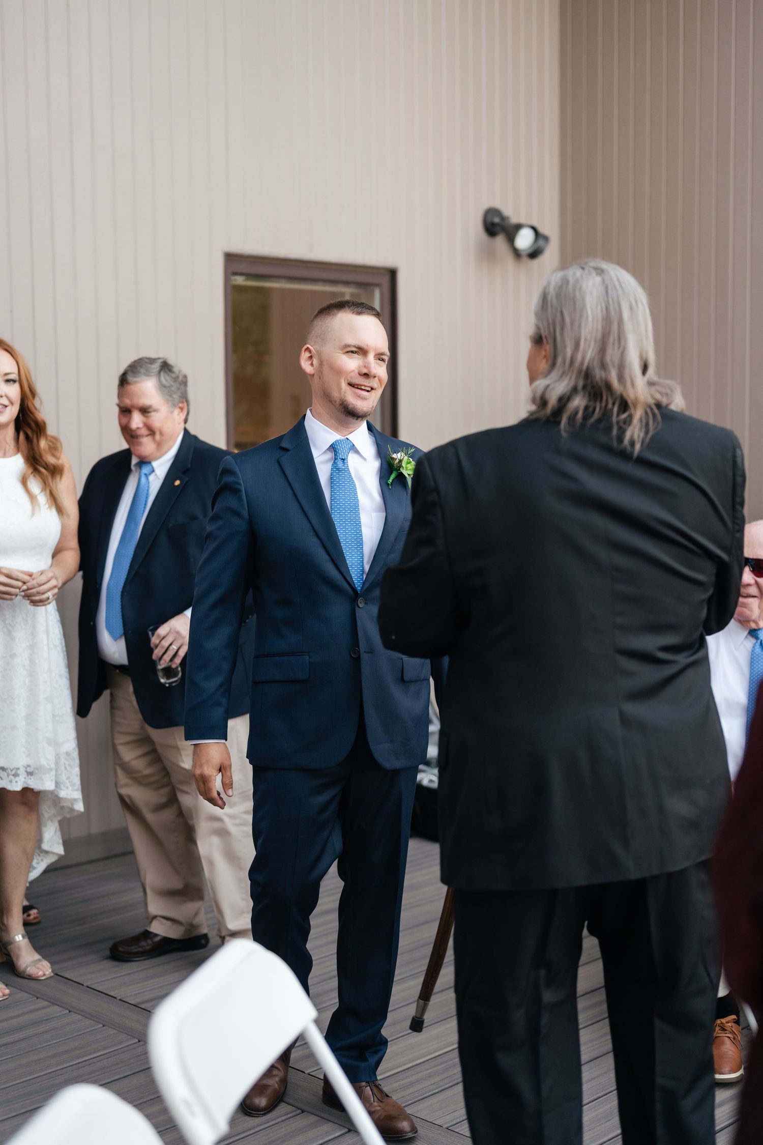 Wedding guests gather on a deck for conversation during reception.