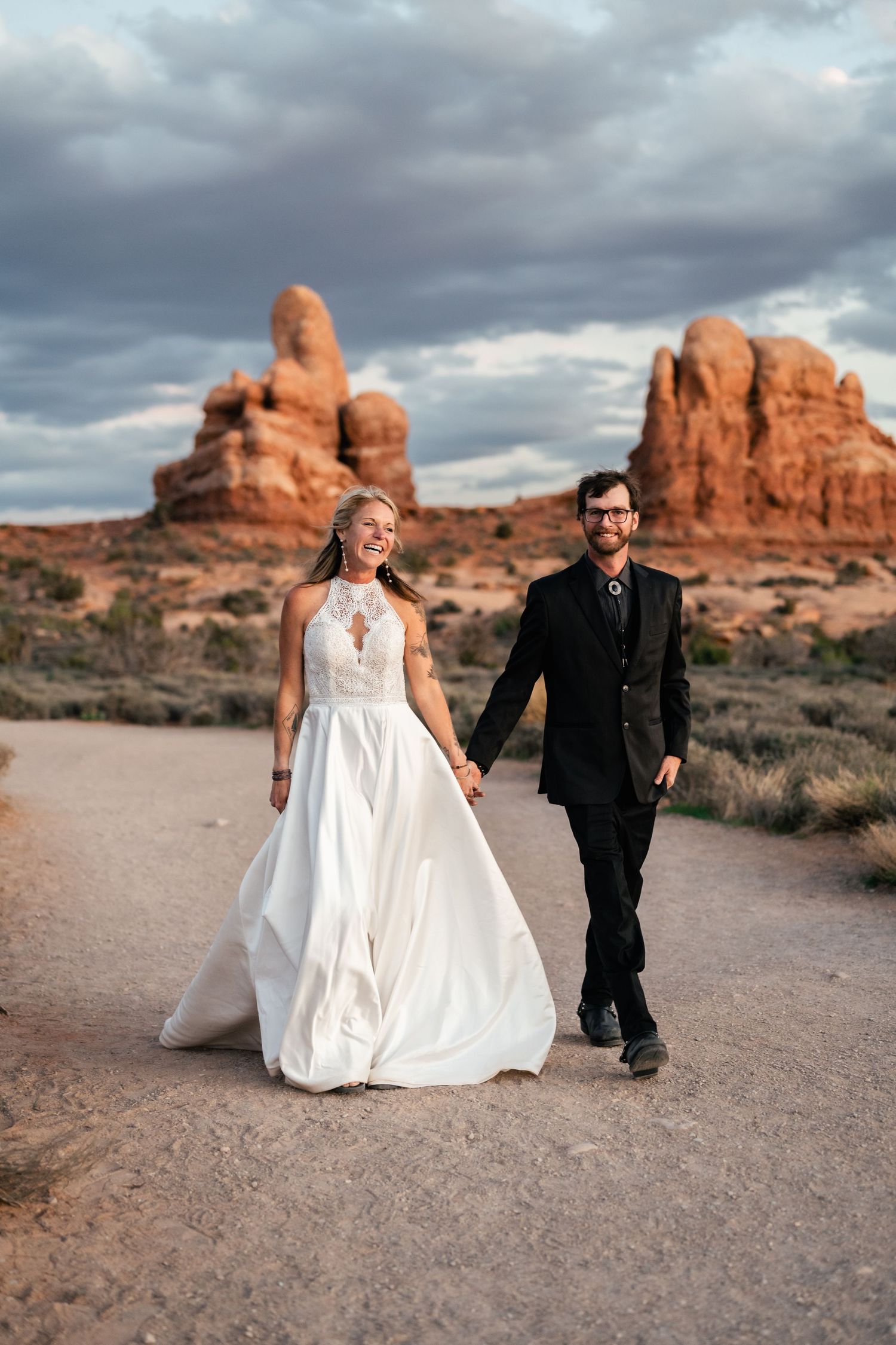 Elopement couple hold hands in Arches National Park by Utah Elopement Photographer and videographer