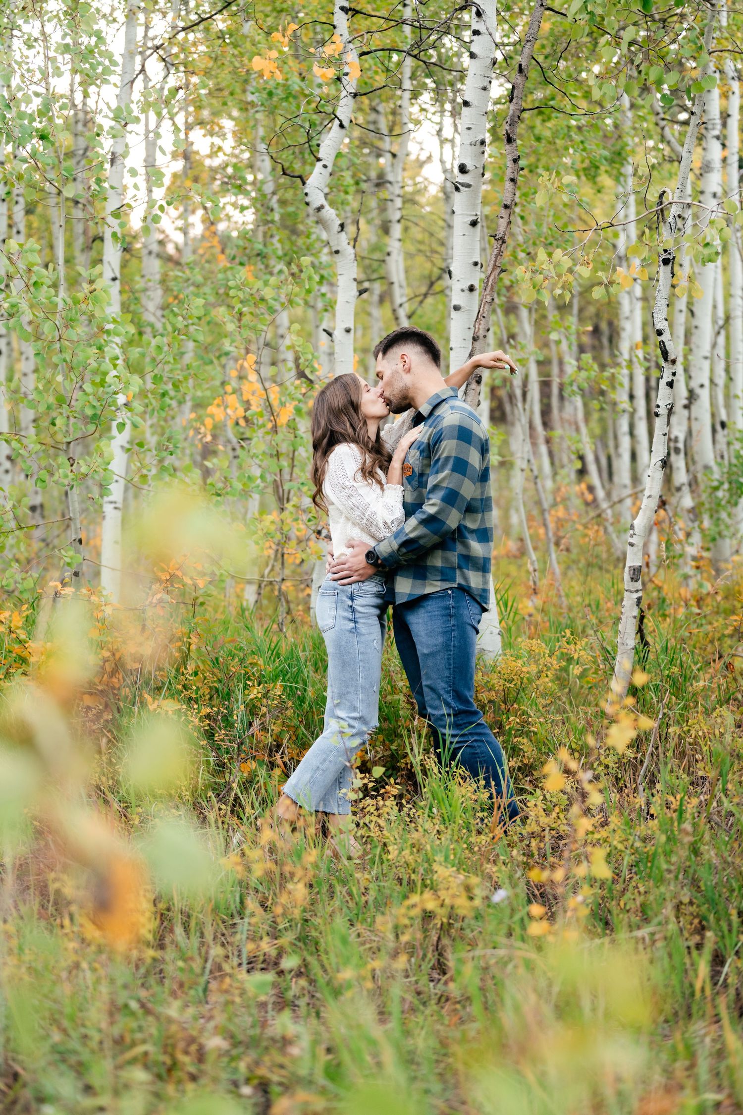 A romantic embrace among white birch trees in a golden autumn forest.