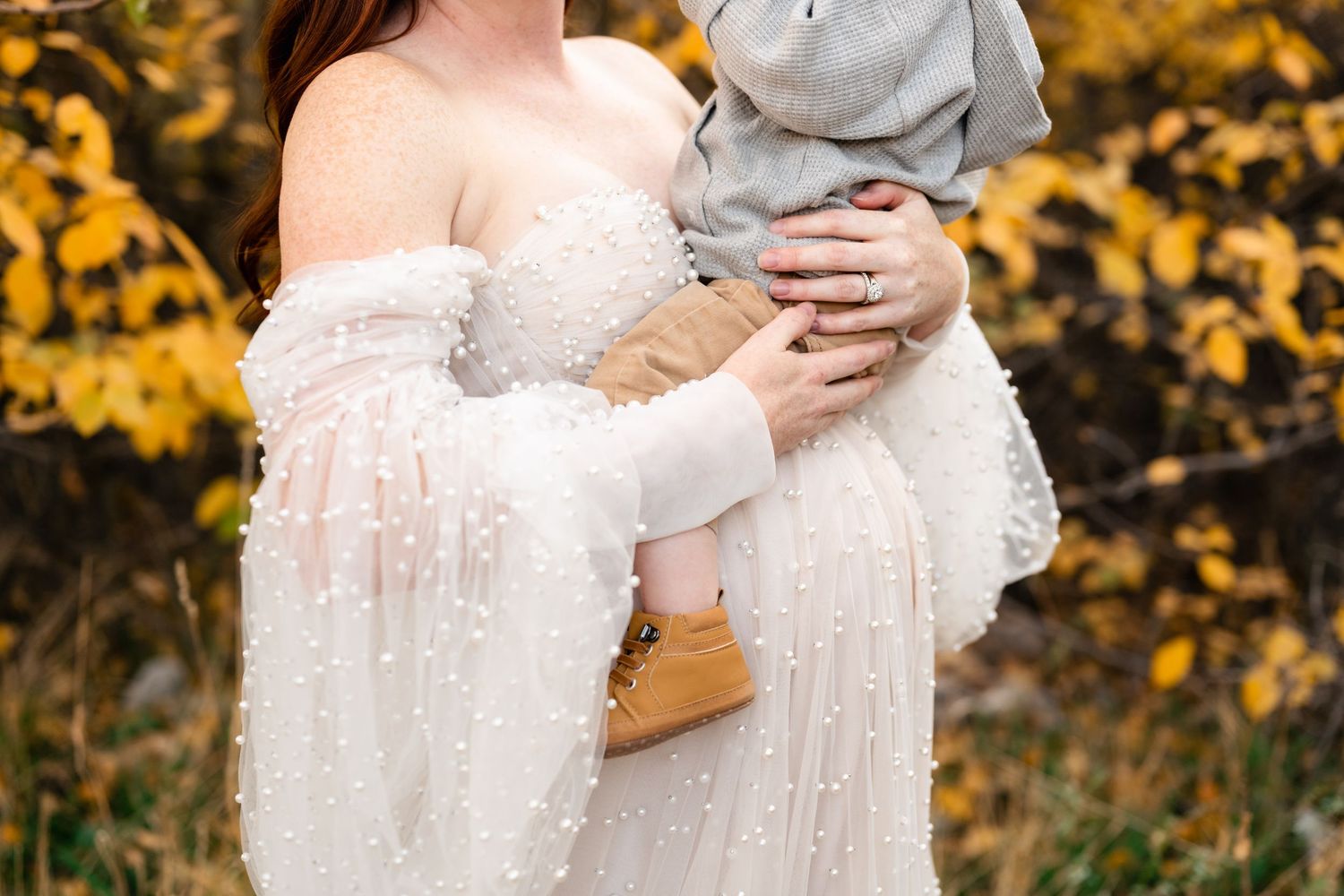 Autumn outdoor maternity photos with golden foliage in the background.