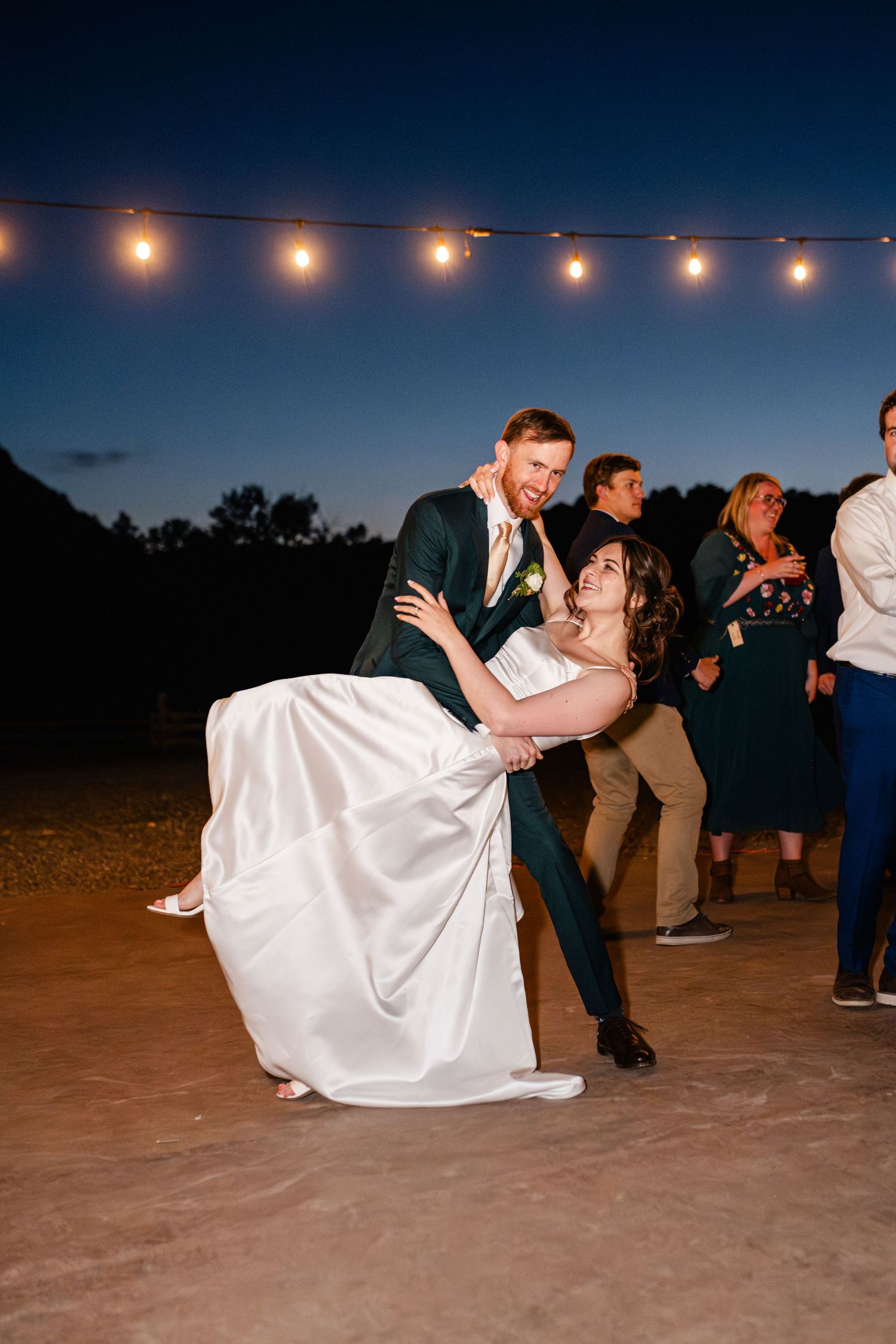 A romantic dip dance sequence at an outdoor evening wedding reception under string lights.
