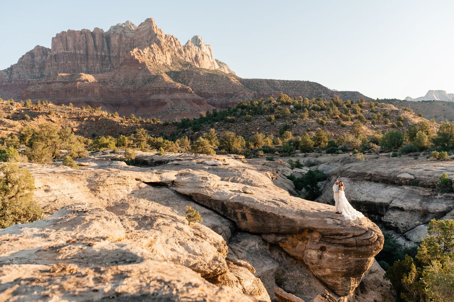 Zion Adventure Session. Wide desert vista showing layered sandstone cliffs and rugged terrain in a national park setting.