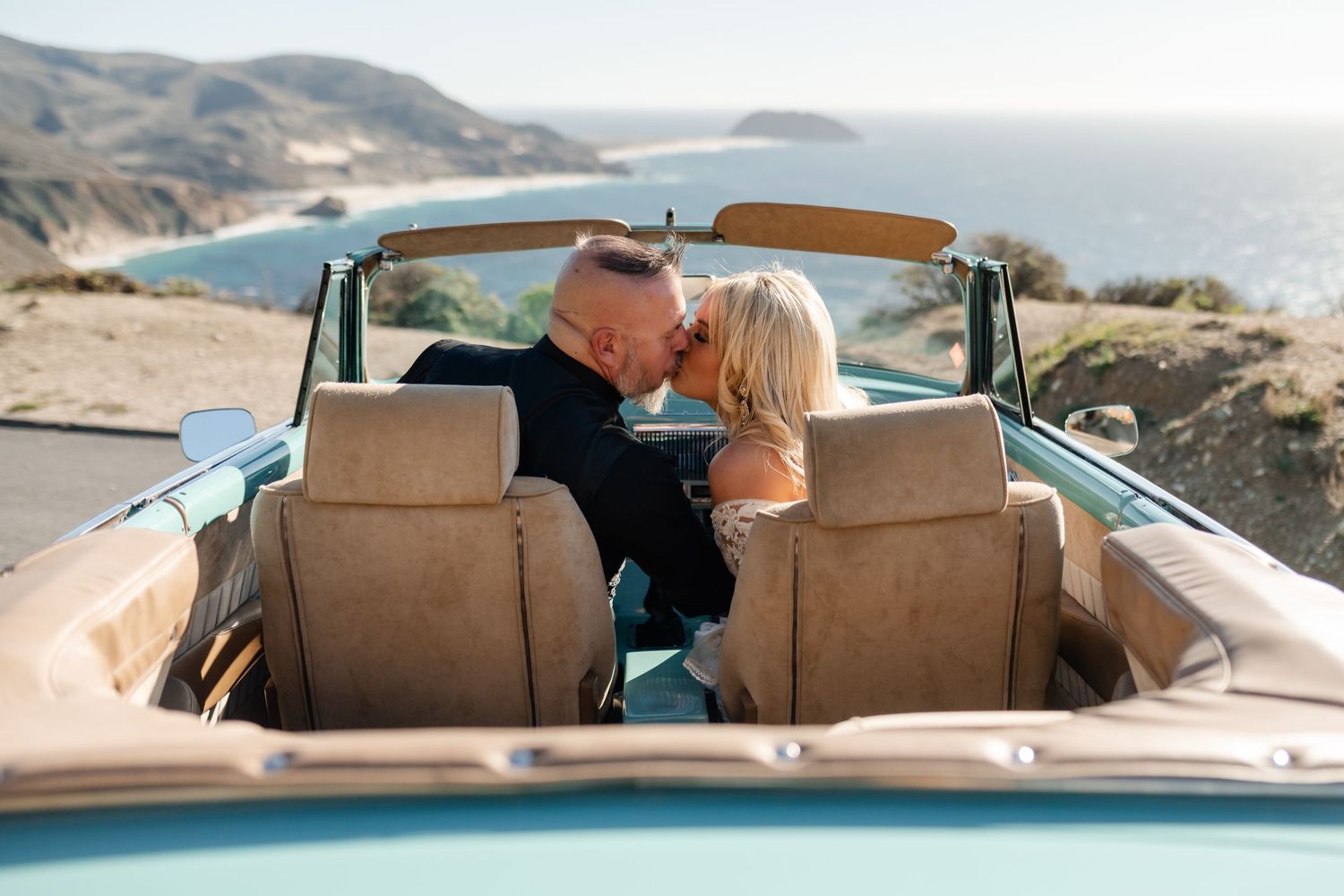 Vintage convertible car driving along scenic coastal road with ocean views.