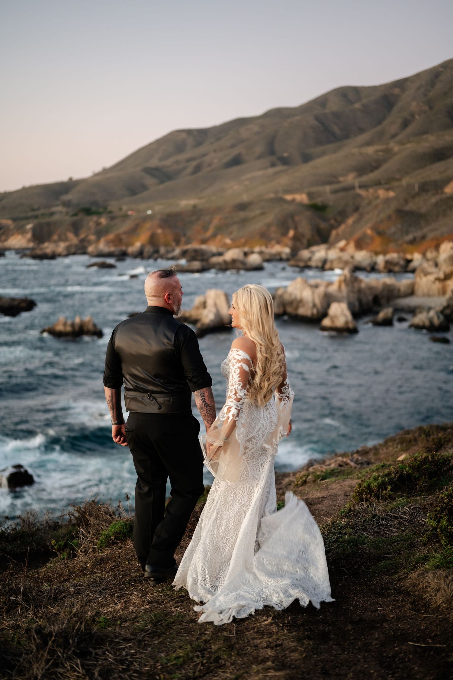 A couple overlooking dramatic Big Sur coastline in wedding attire.
