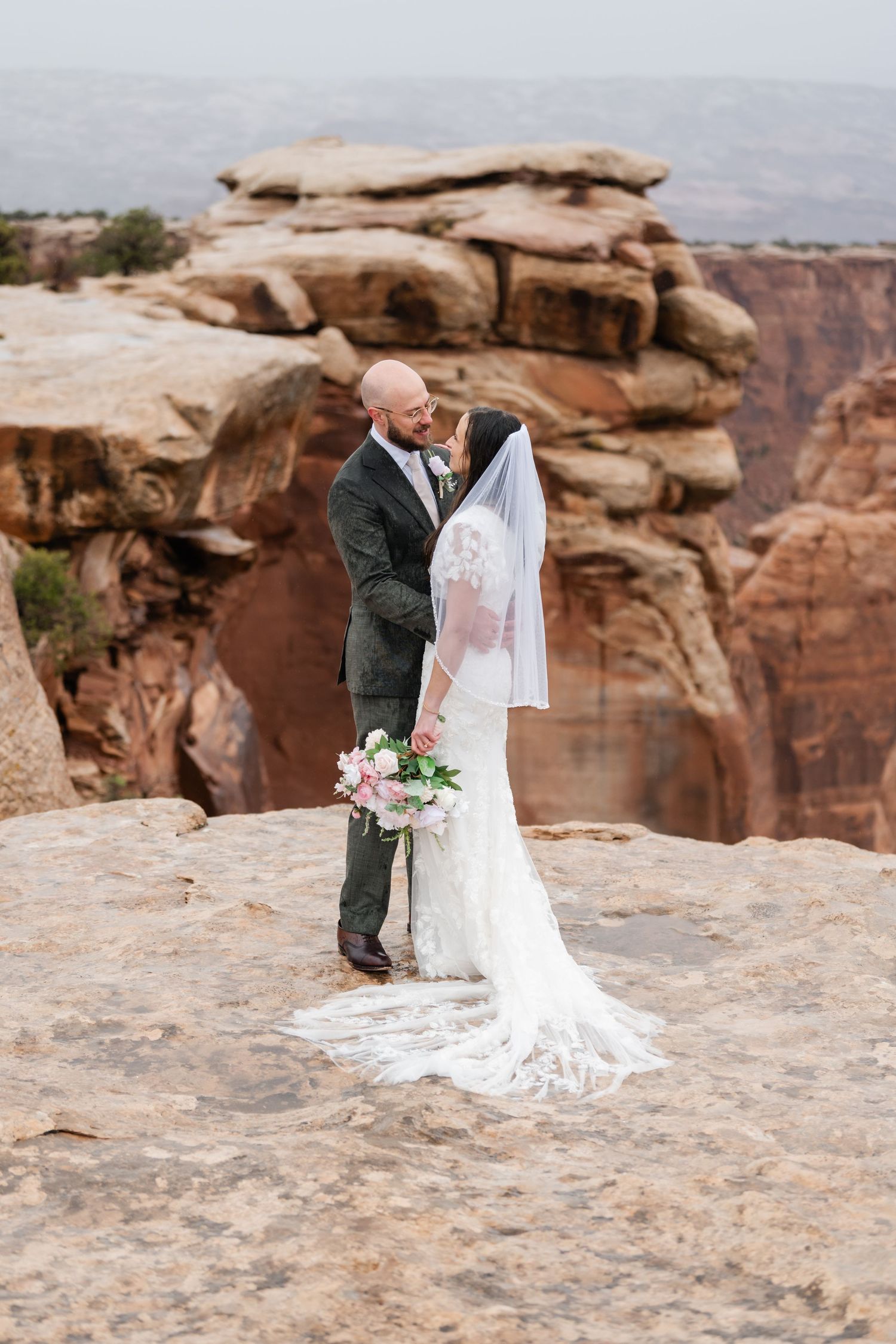 A wedding couple shares tender moments during their canyon-edge photo session.
