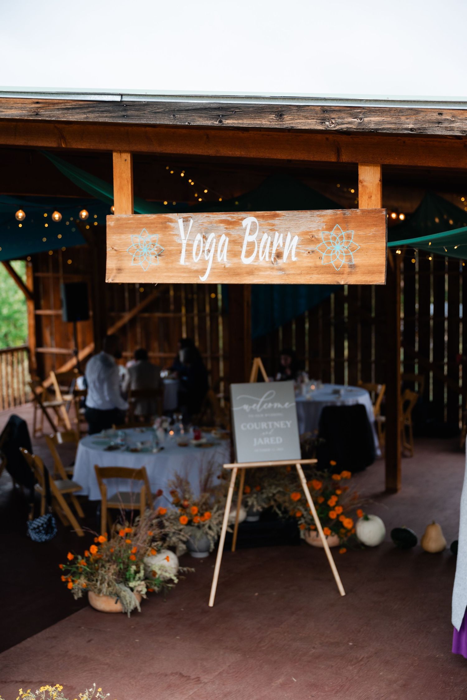 Rustic barn venue decorated with string lights and wooden beams for a wedding reception.