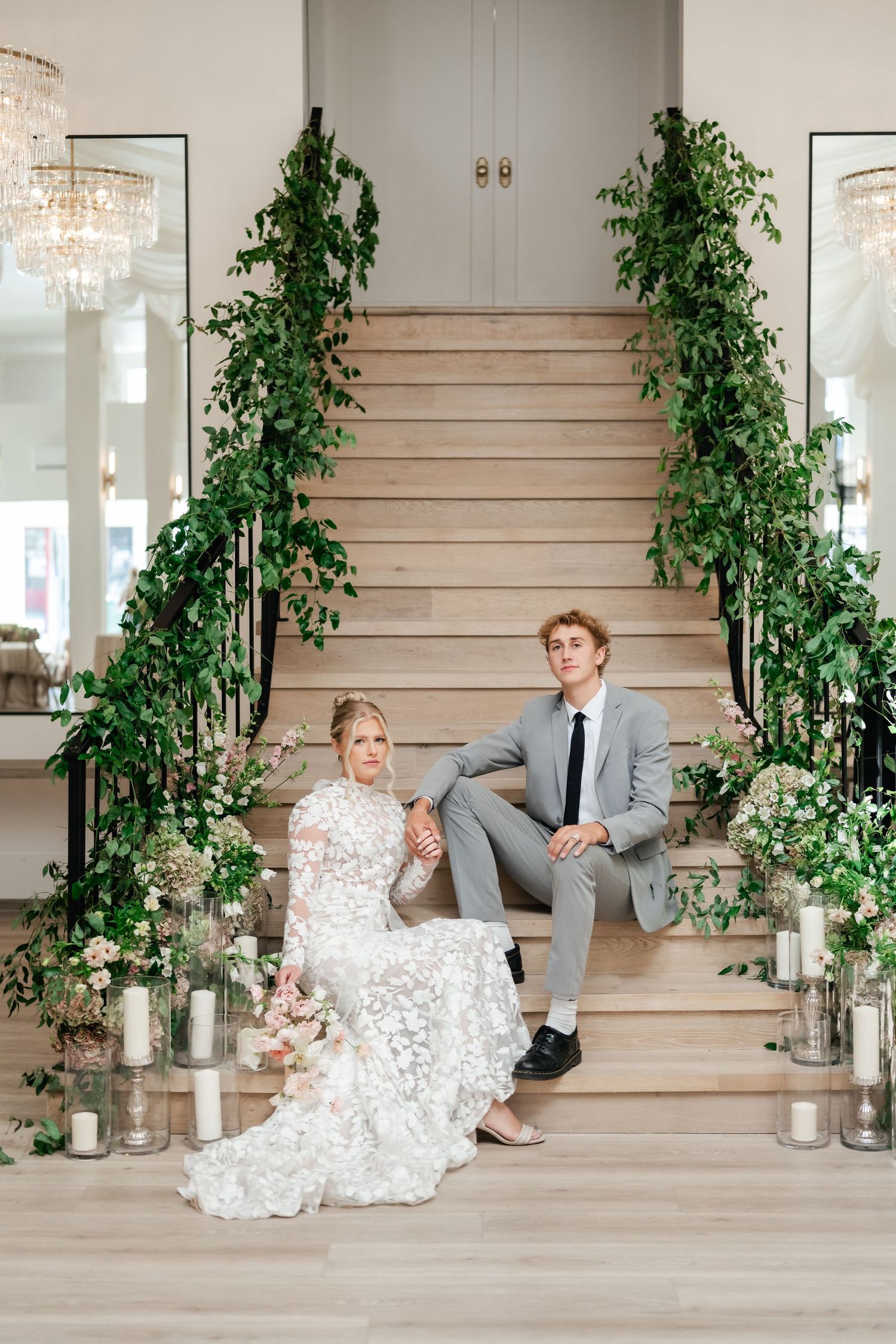 Wedding couple sits on the grand staircase surrounded by florals and candles at Moments on Main photo by preferred vendor Coley Cook.