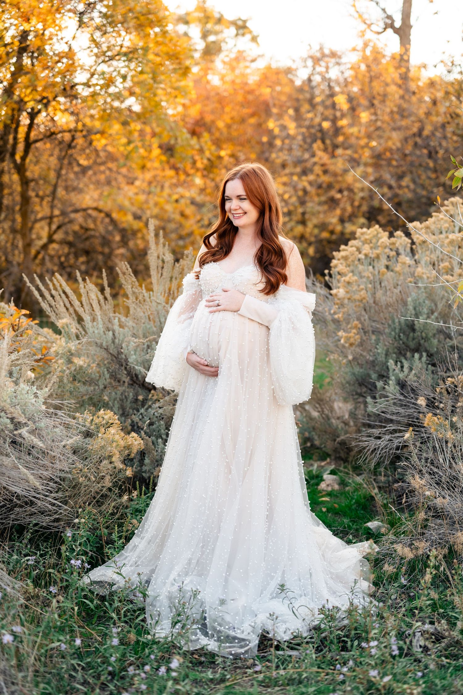 A dreamy outdoor photoshoot in golden autumn light with flowing white lace dress among wild sage brush and tall grass.