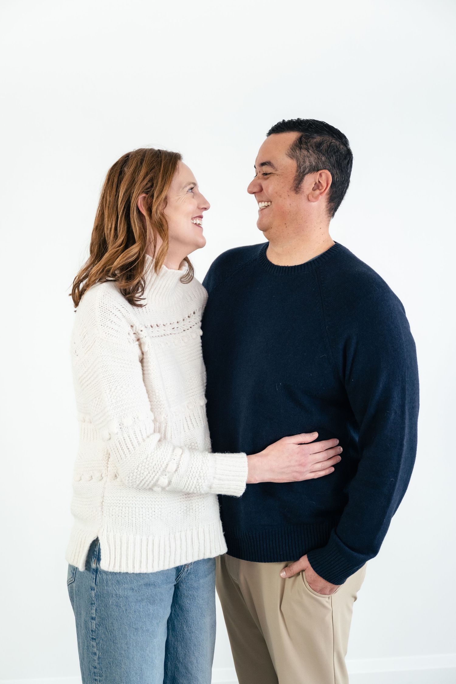 A couple in casual attire shares a tender moment against a white background in a three-part photo series.