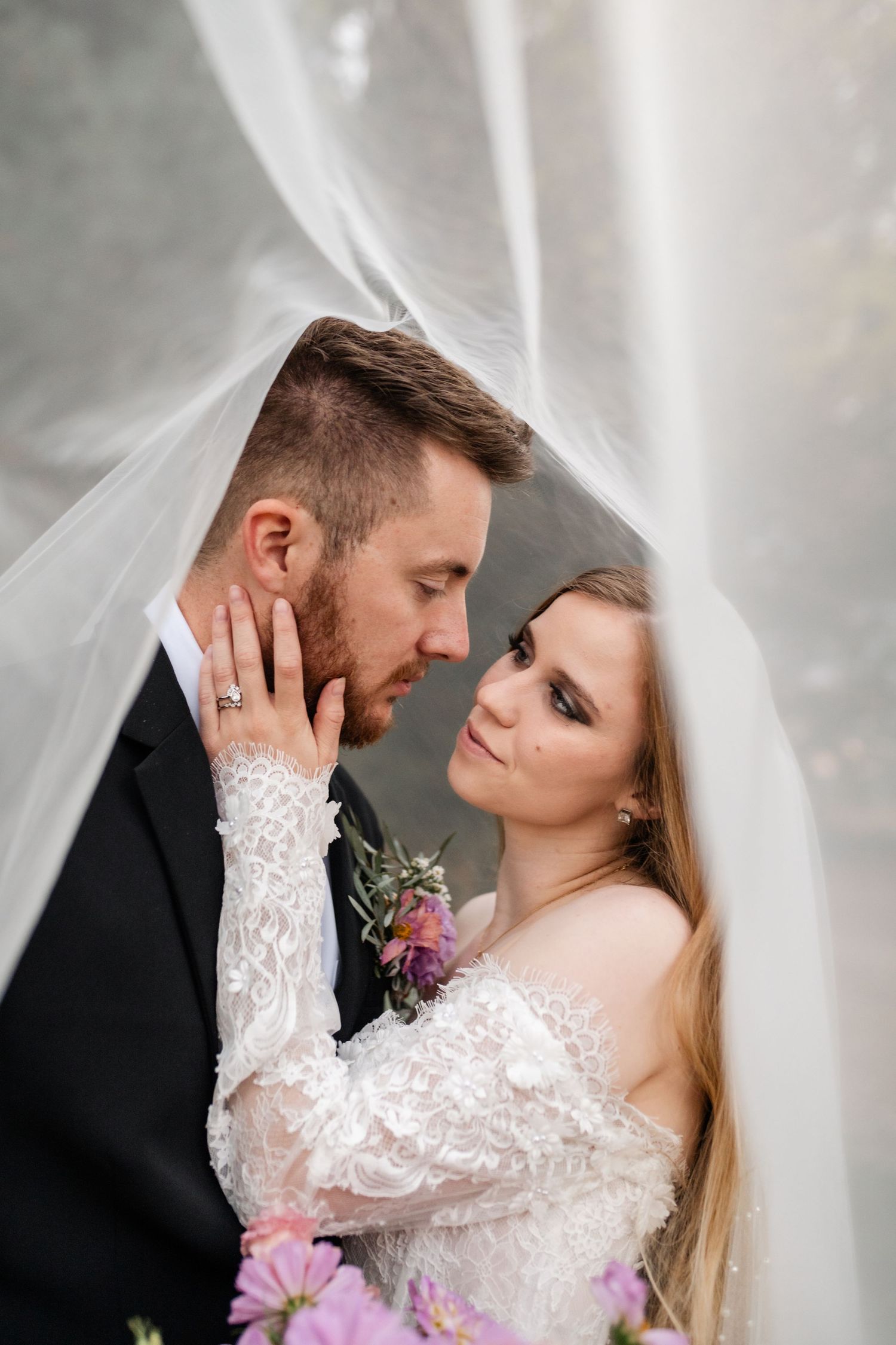 Romantic wedding portrait under white veil with bride in lace dress and groom in black suit. Utah Wedding Photographer Coley Cook.
