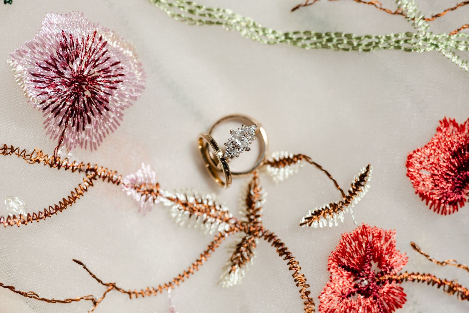 Delicate pink and coral paper pom pom decorations arranged with twine and greenery on a light background.