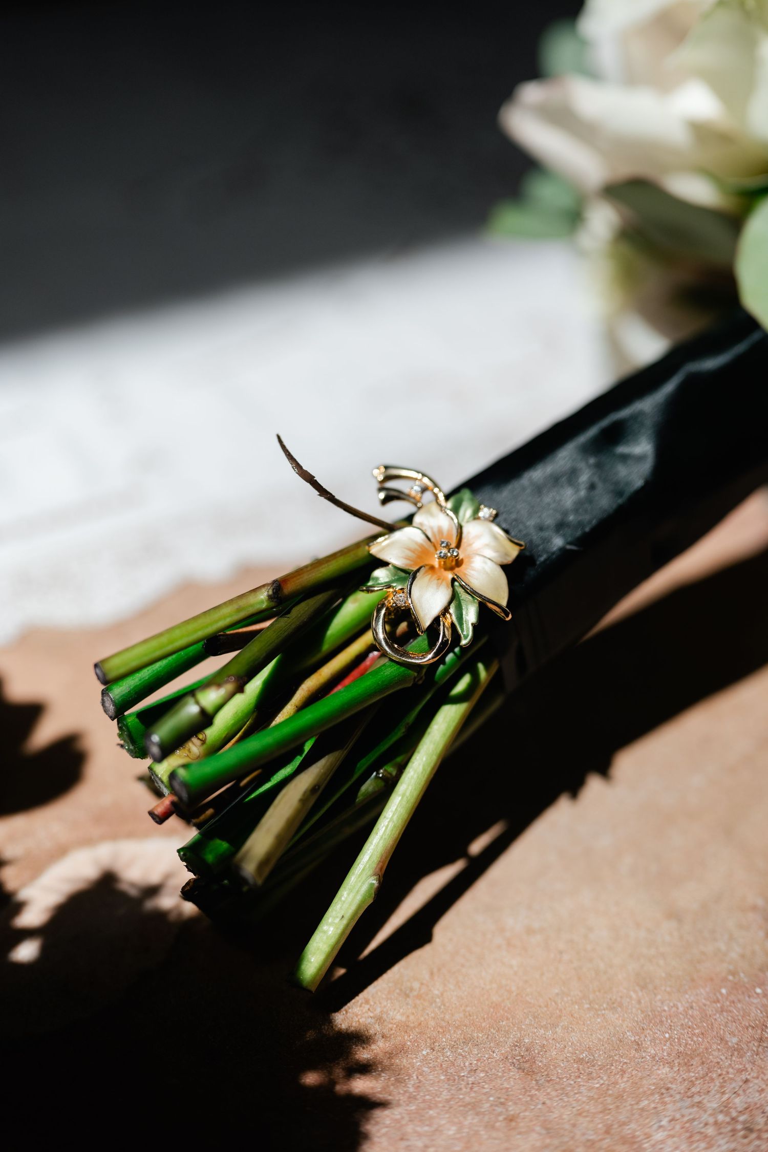 Close-up shots of white floral boutonnieres with green stems against a dark background.