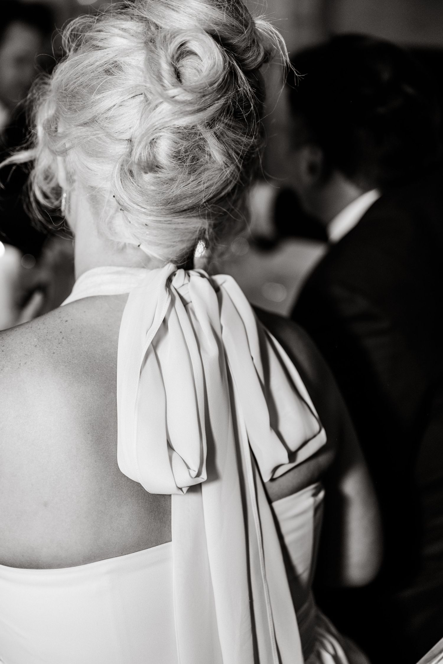 Back view of an elegant white dress with a dramatic bow detail and upswept hairstyle.