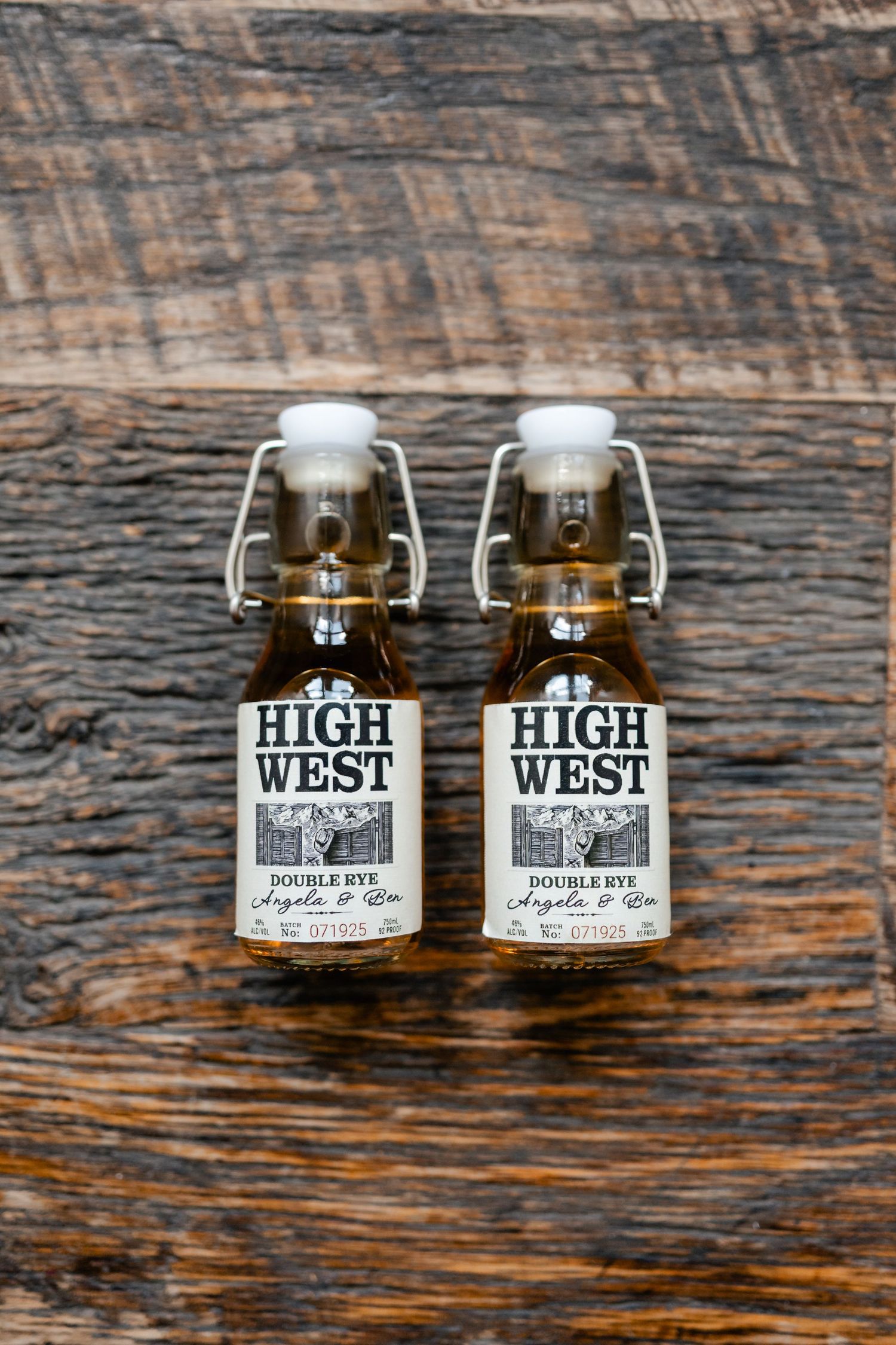 Four vintage-style glass bottles with High West whiskey labels arranged on rustic wooden surface.