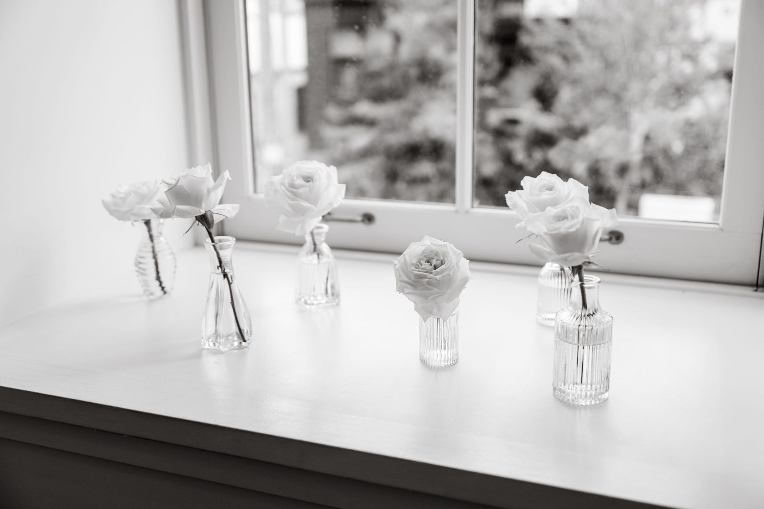 Elegant glassware and vases arranged on a white windowsill with natural light streaming in.