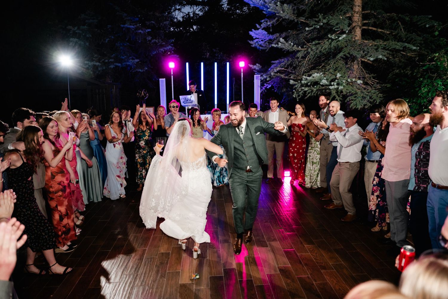 Wedding reception dance floor lit with colorful lights as guests celebrate. Millcreek Inn Wedding Photographer. Outdoor reception photos.