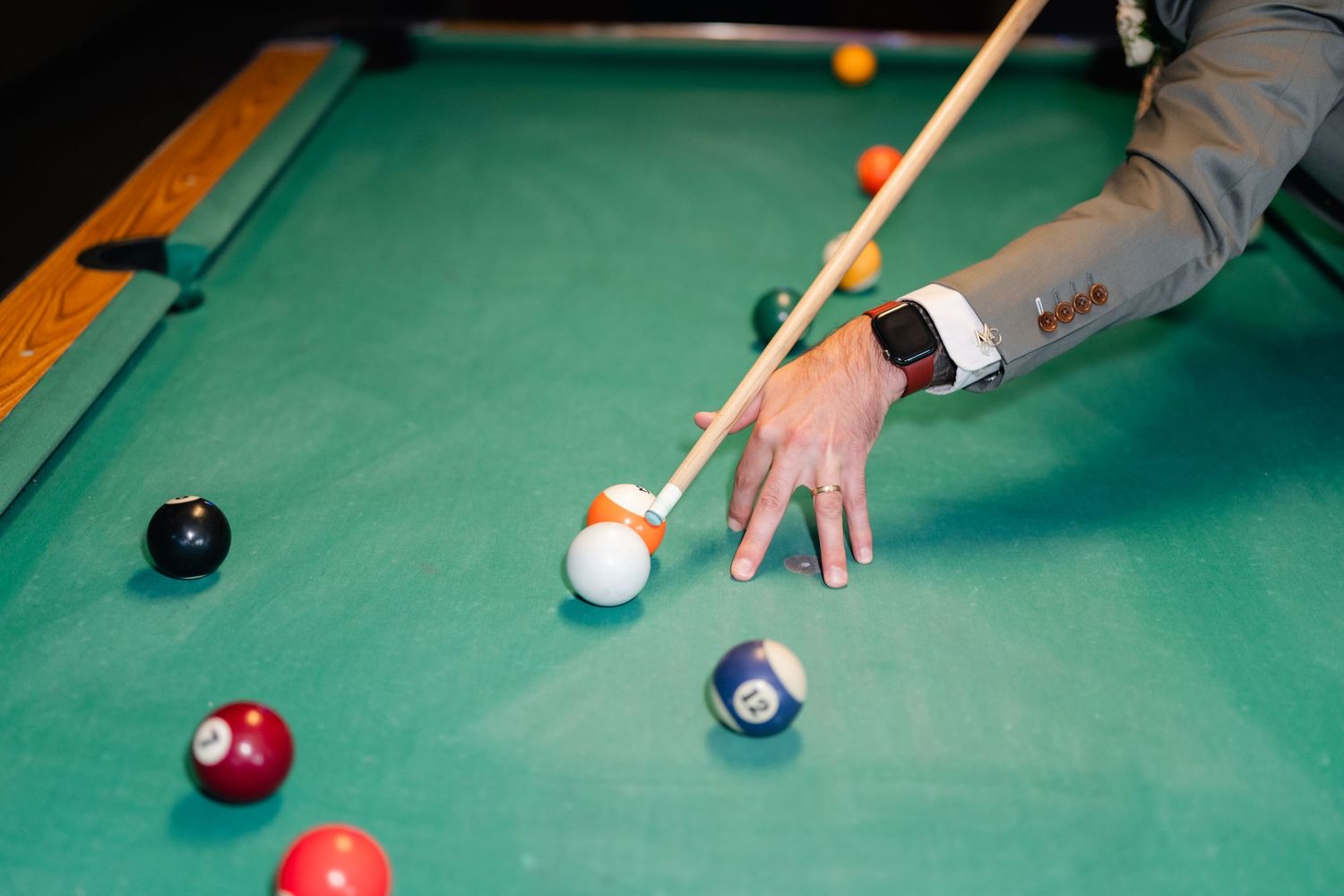 Close-up of hands lining up a shot on a pool table with colorful balls.